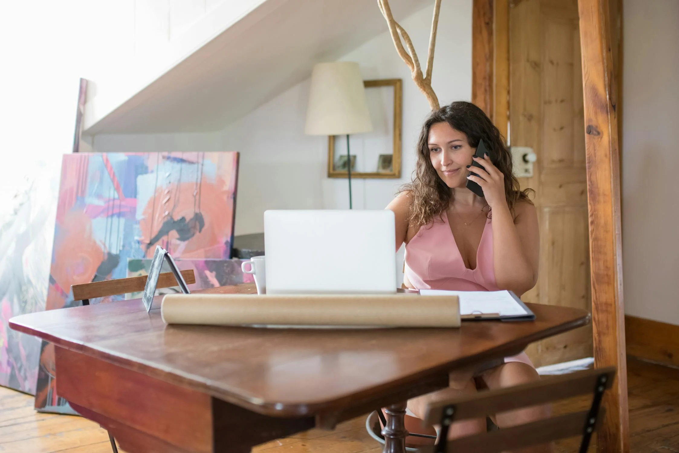 A woman talking on her phone and looking at her laptop | Source: Pexels