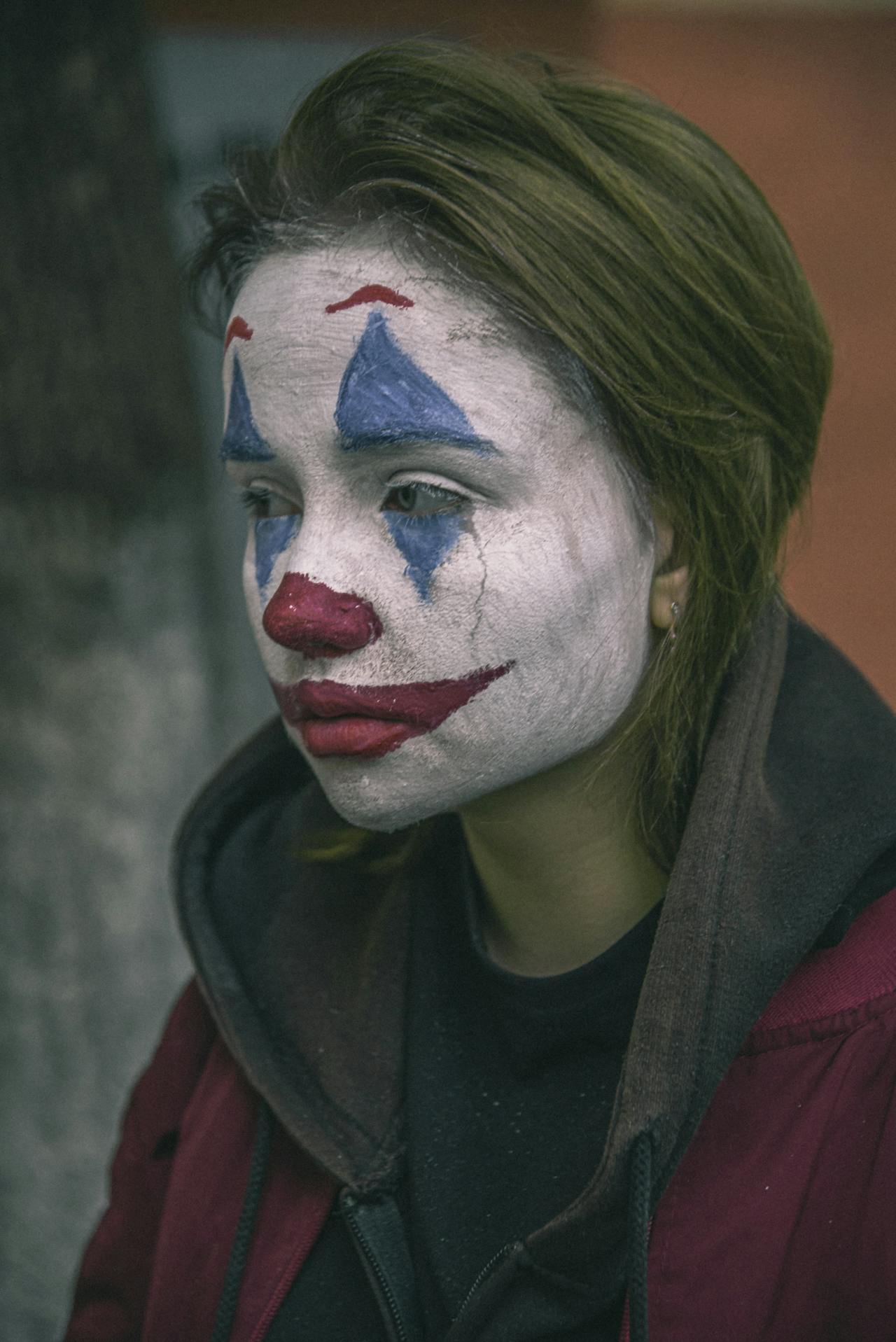 A distressed woman with her face painted to depict a clown | Source: Pexels