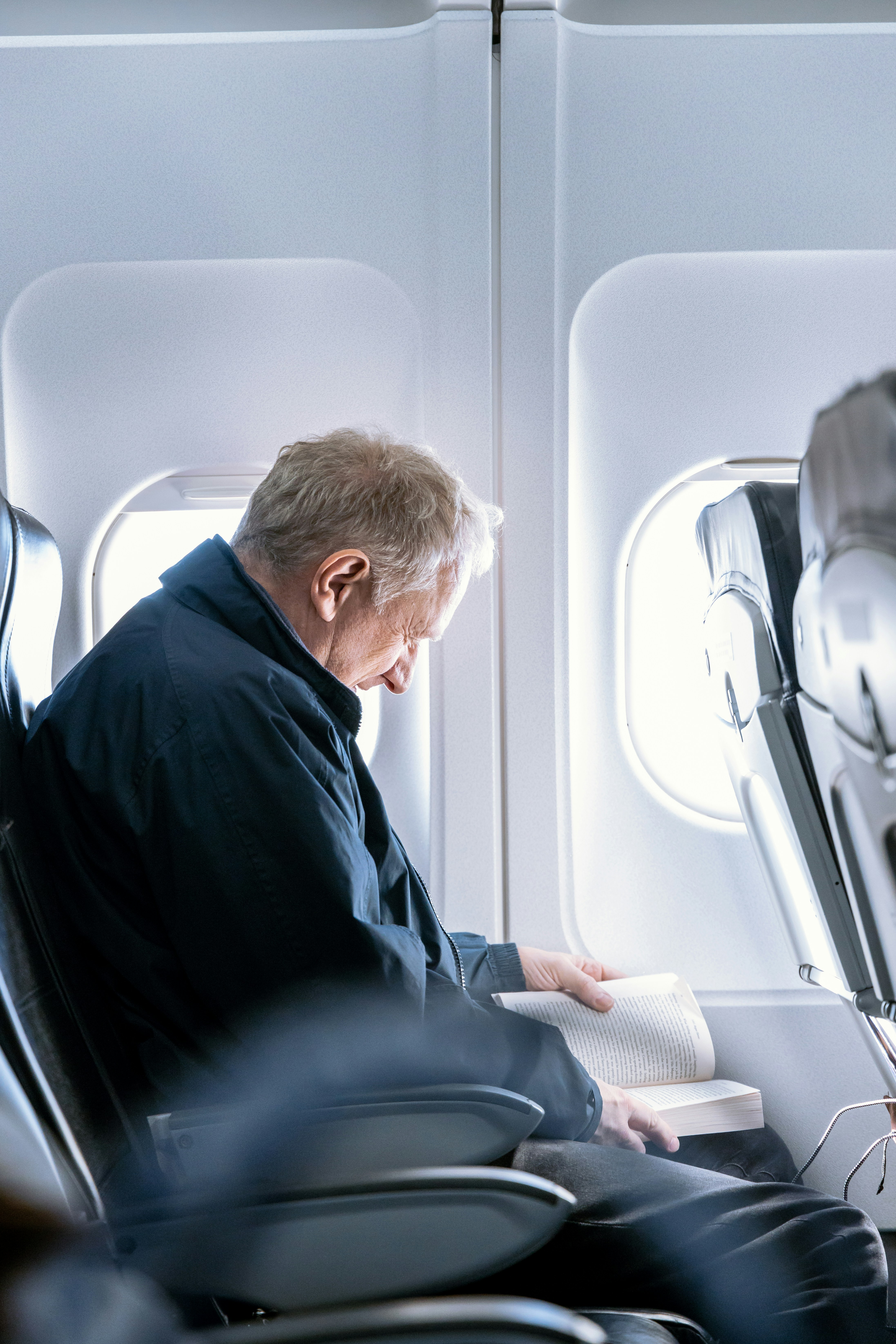 Man reading a book inside a plane | Source: Unsplash