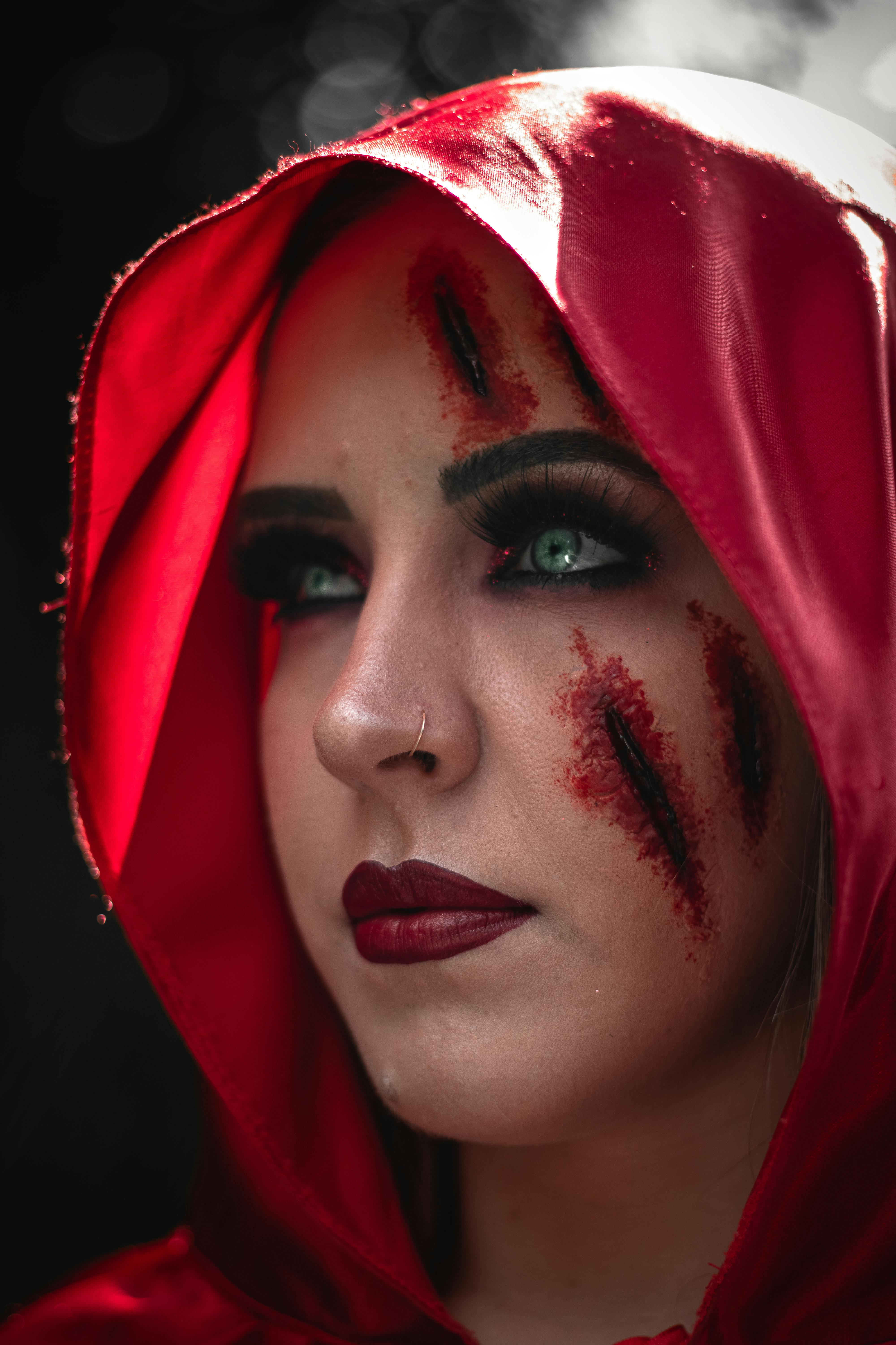 A close-up of a woman with a red hood and a bloody wound on her face | Source: Pexels