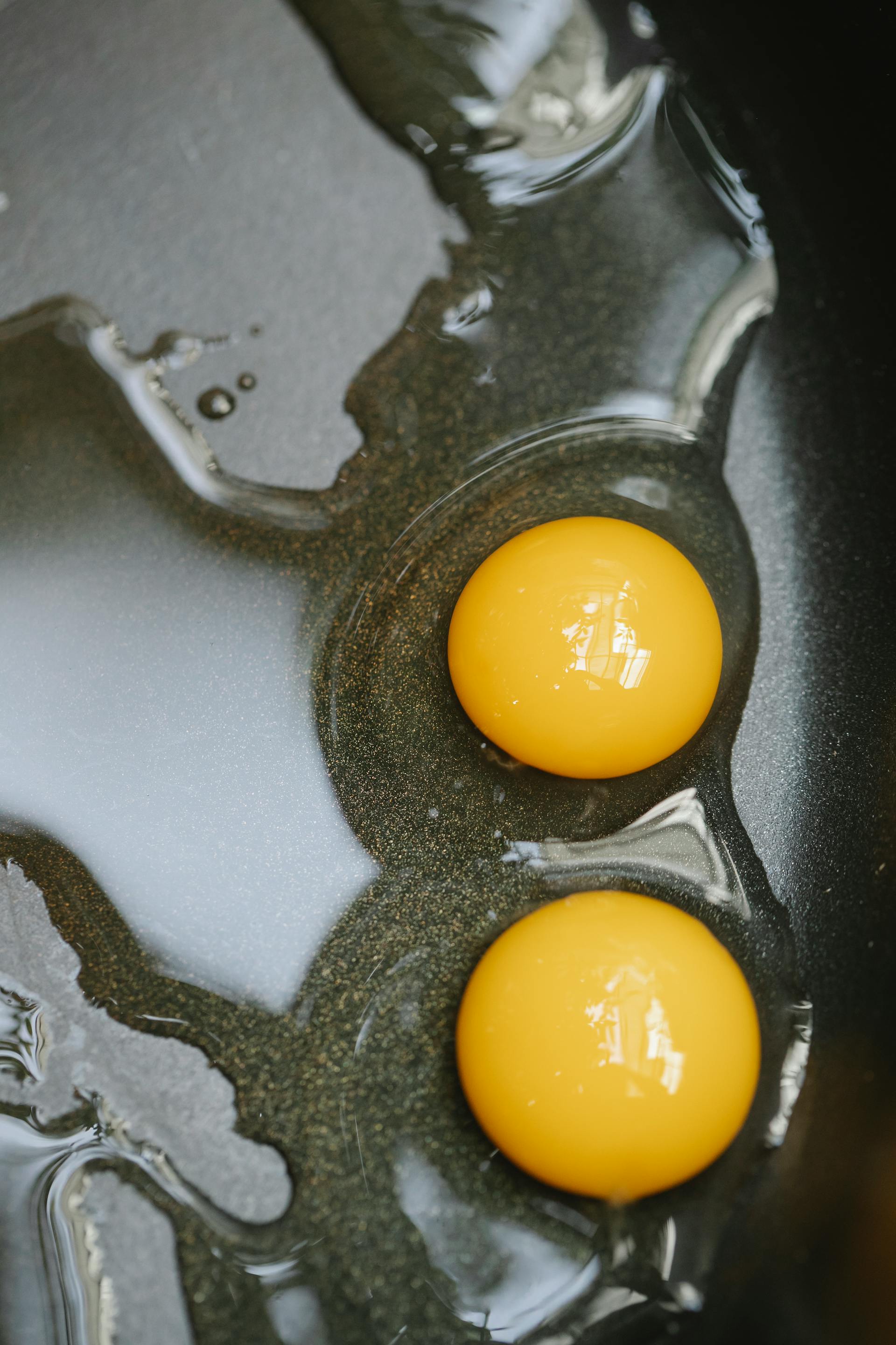 A closeup shot of eggs frying in a black pan | Source: Pexels