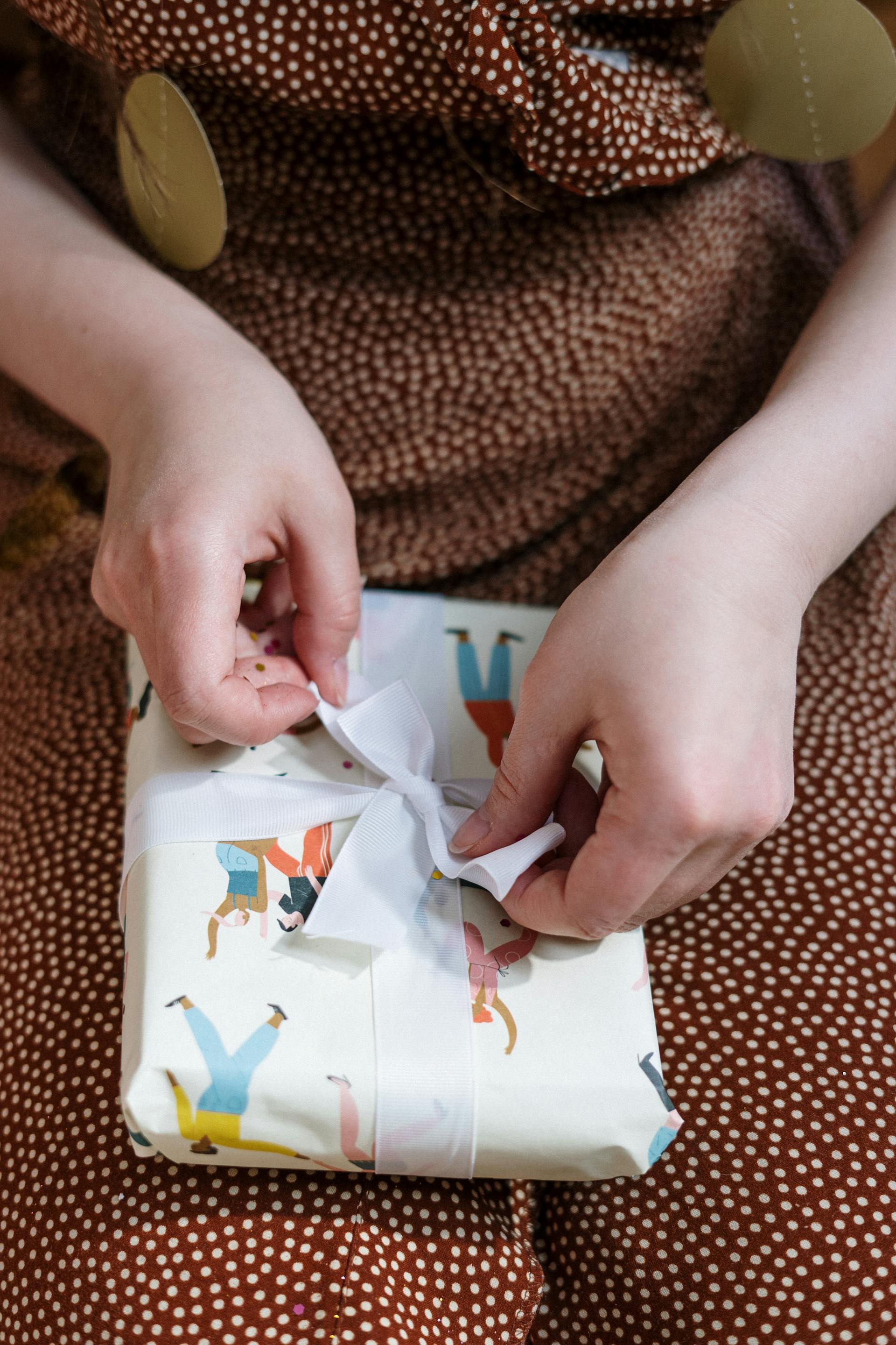A close-up shot of a woman tying the bow of a gift box | Source: Pexels