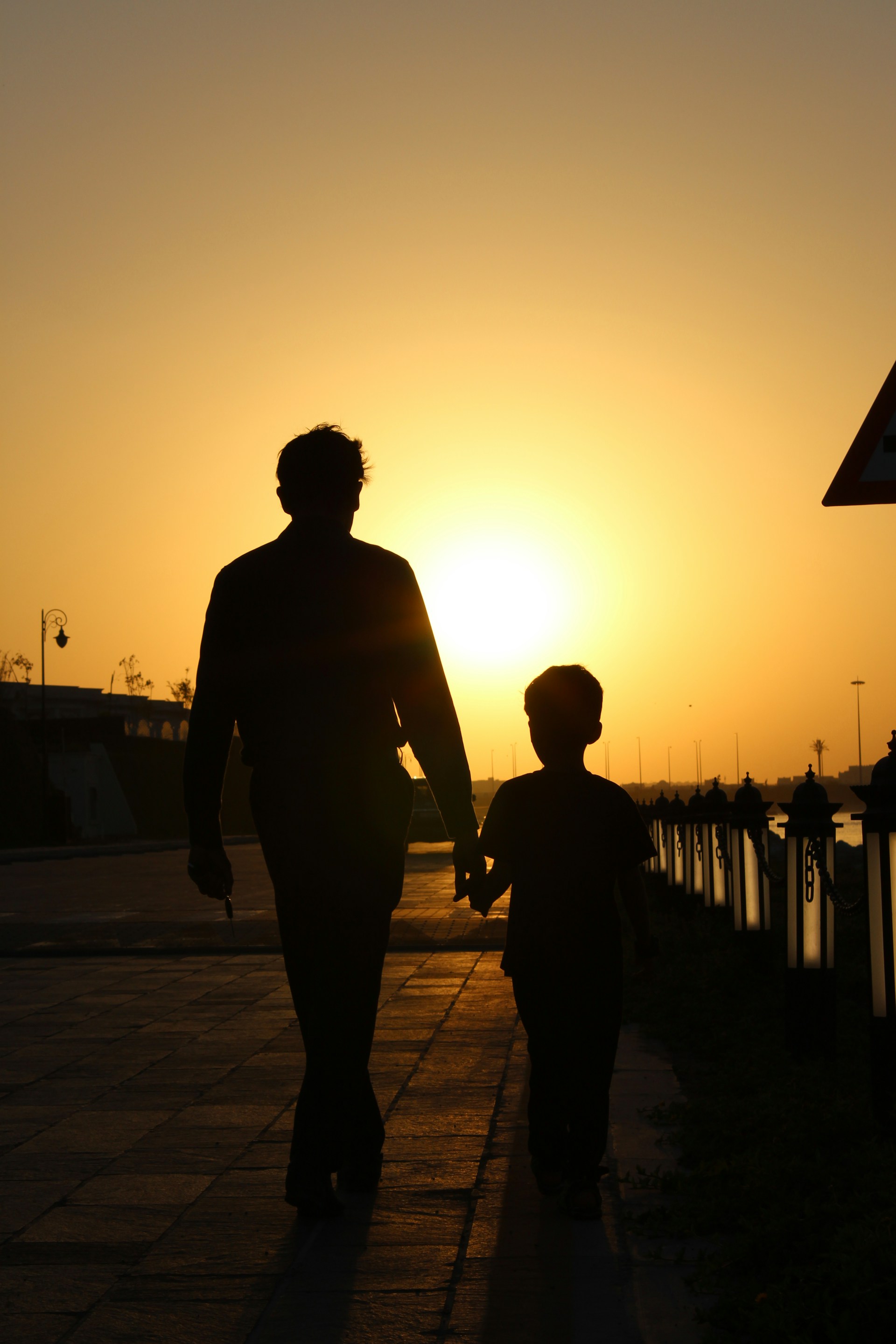 Silhouette of a father and son walking on the street | Source: Unsplash