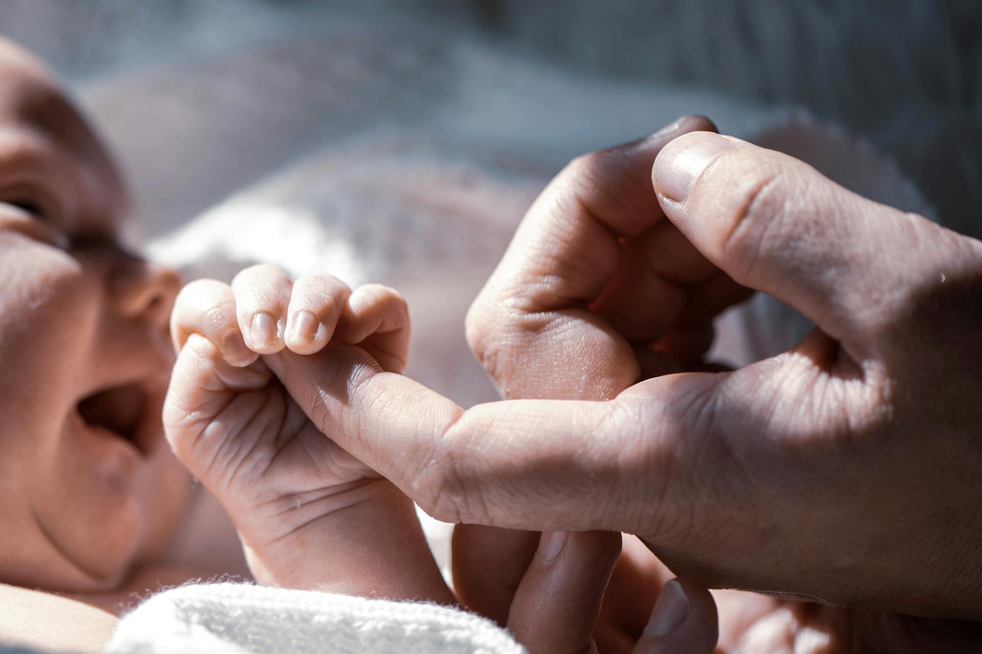 A baby holding a man's finger | Source: Pexels