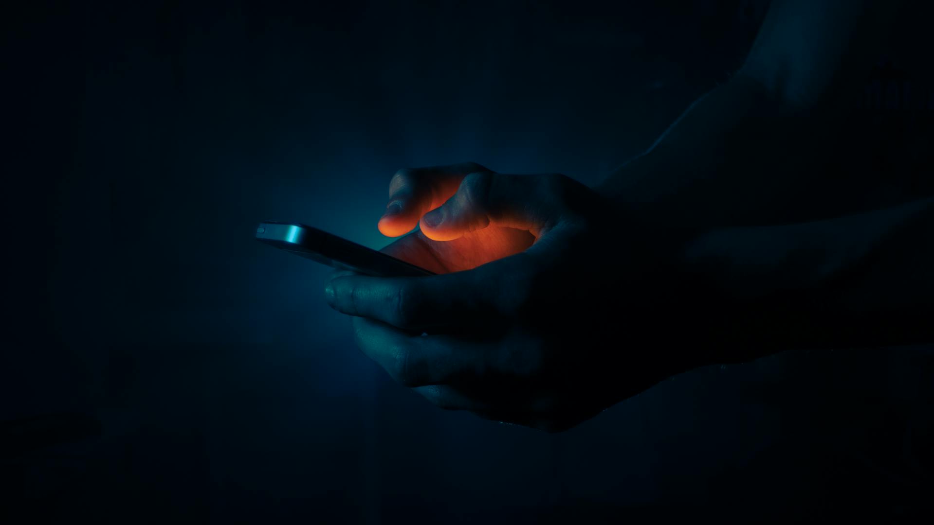 A man holding a phone in the dark | Source: Pexels