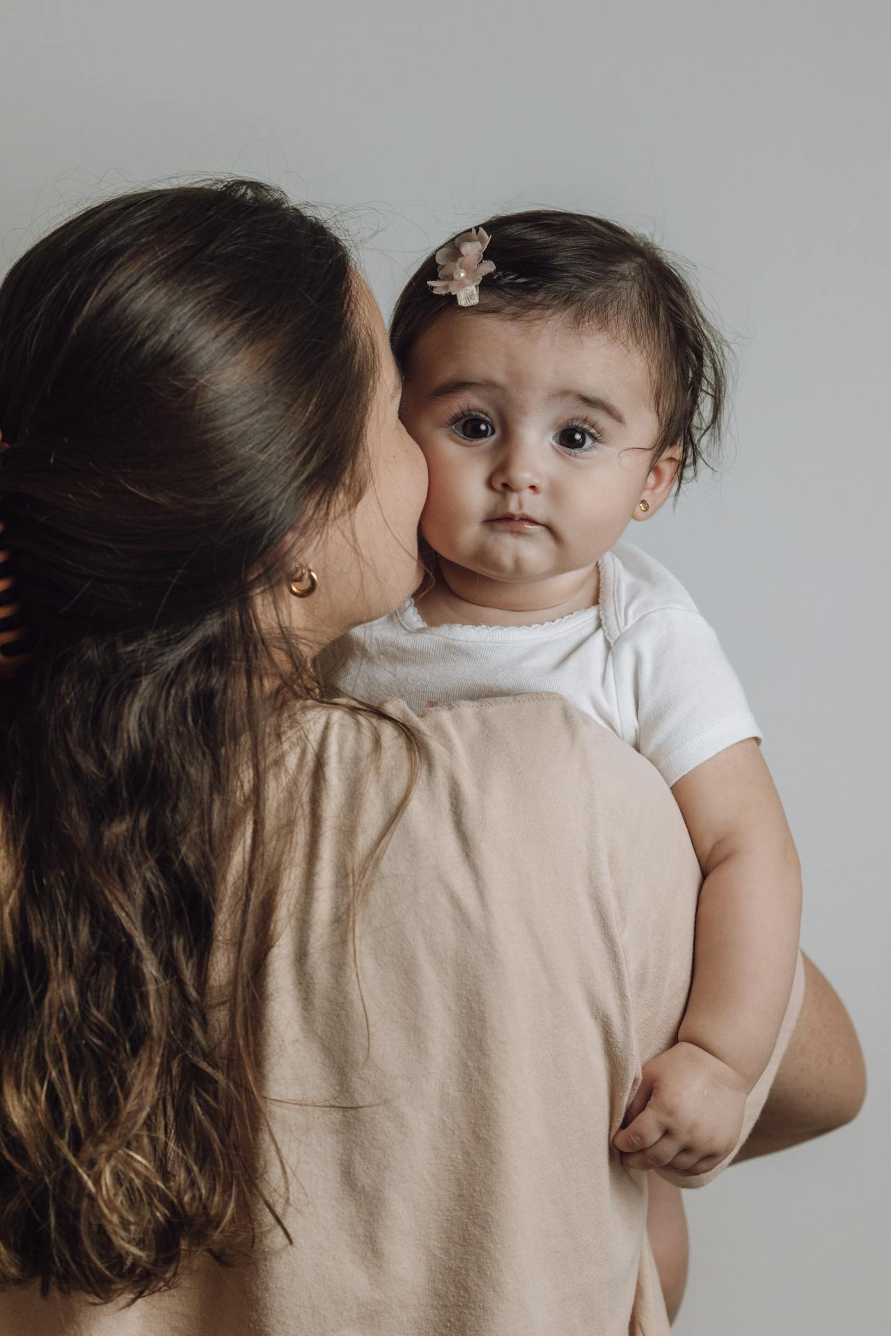 A delighted mother carrying an adorable baby girl | Source: Pexels
