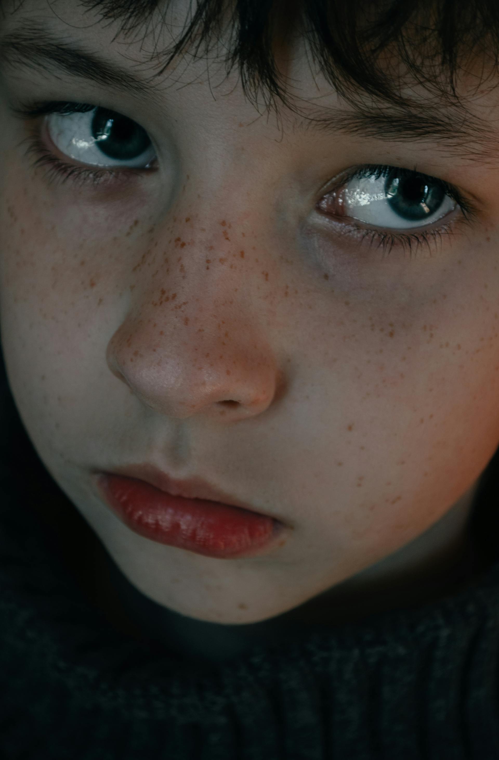 A sad child with freckles and blue eyes | Source: Pexels