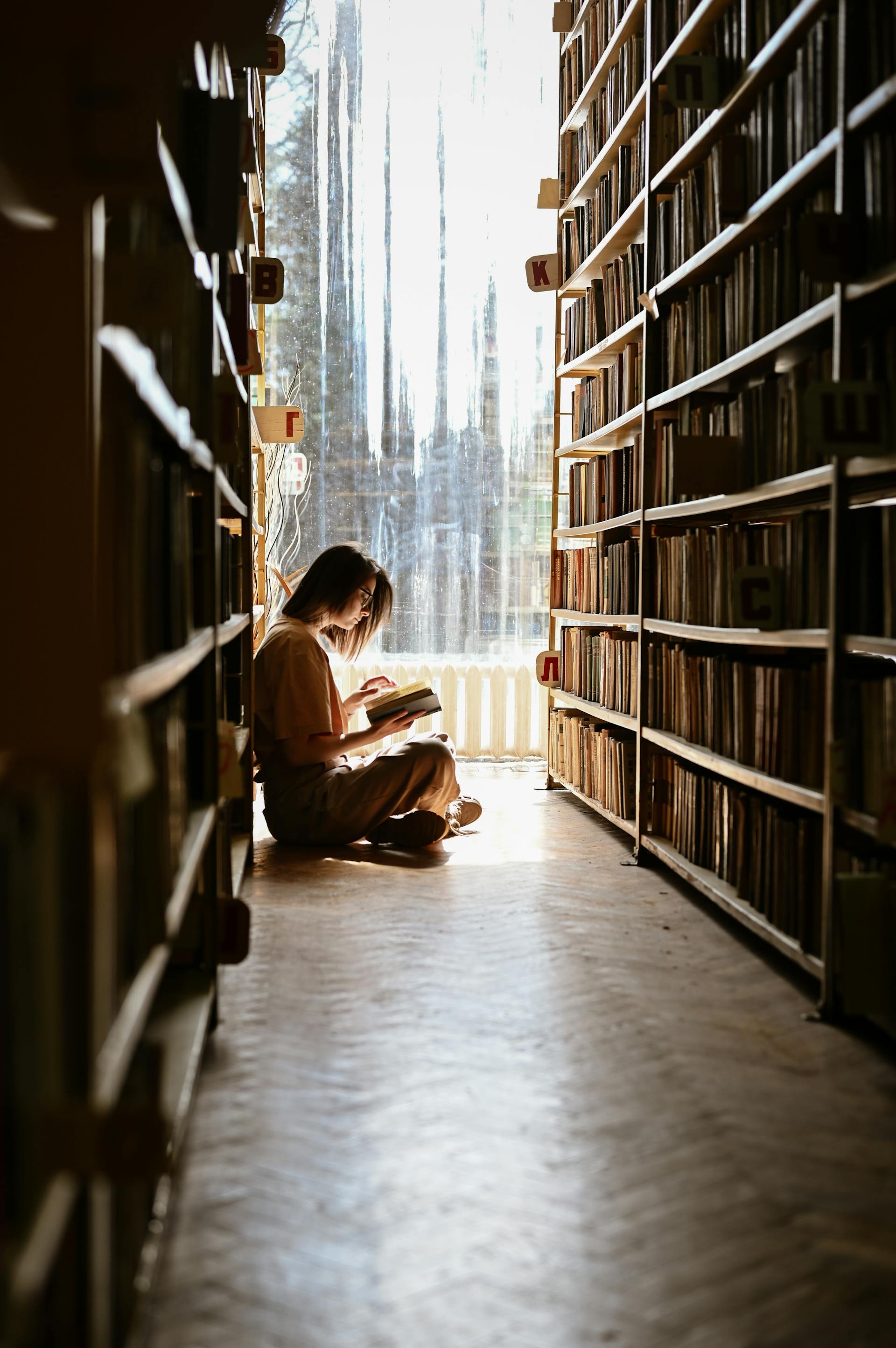 A woman sitting on the floor and reading a book | Source: Pexels