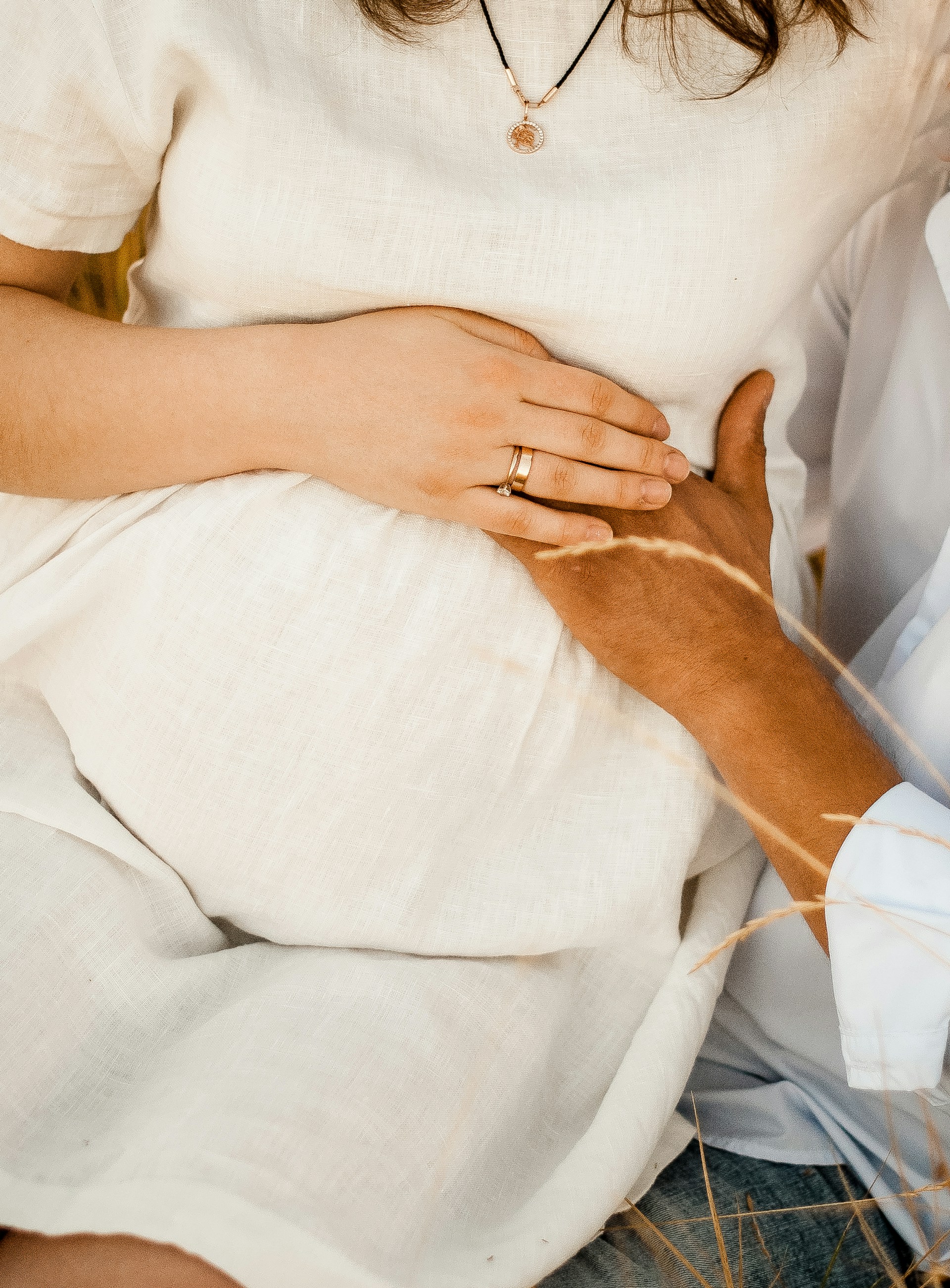 A pregnant woman sitting on a man's lap as he gently touches her baby bump | Source: Unsplash