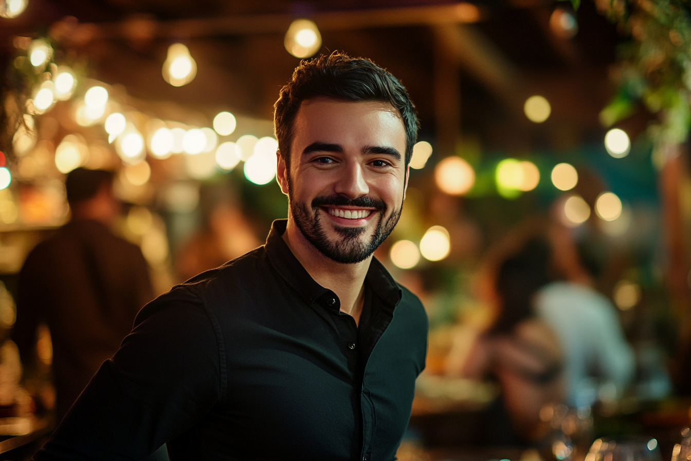 Un hombre sonriendo cálidamente, de pie en un agradable restaurante | Fuente: Midjourney