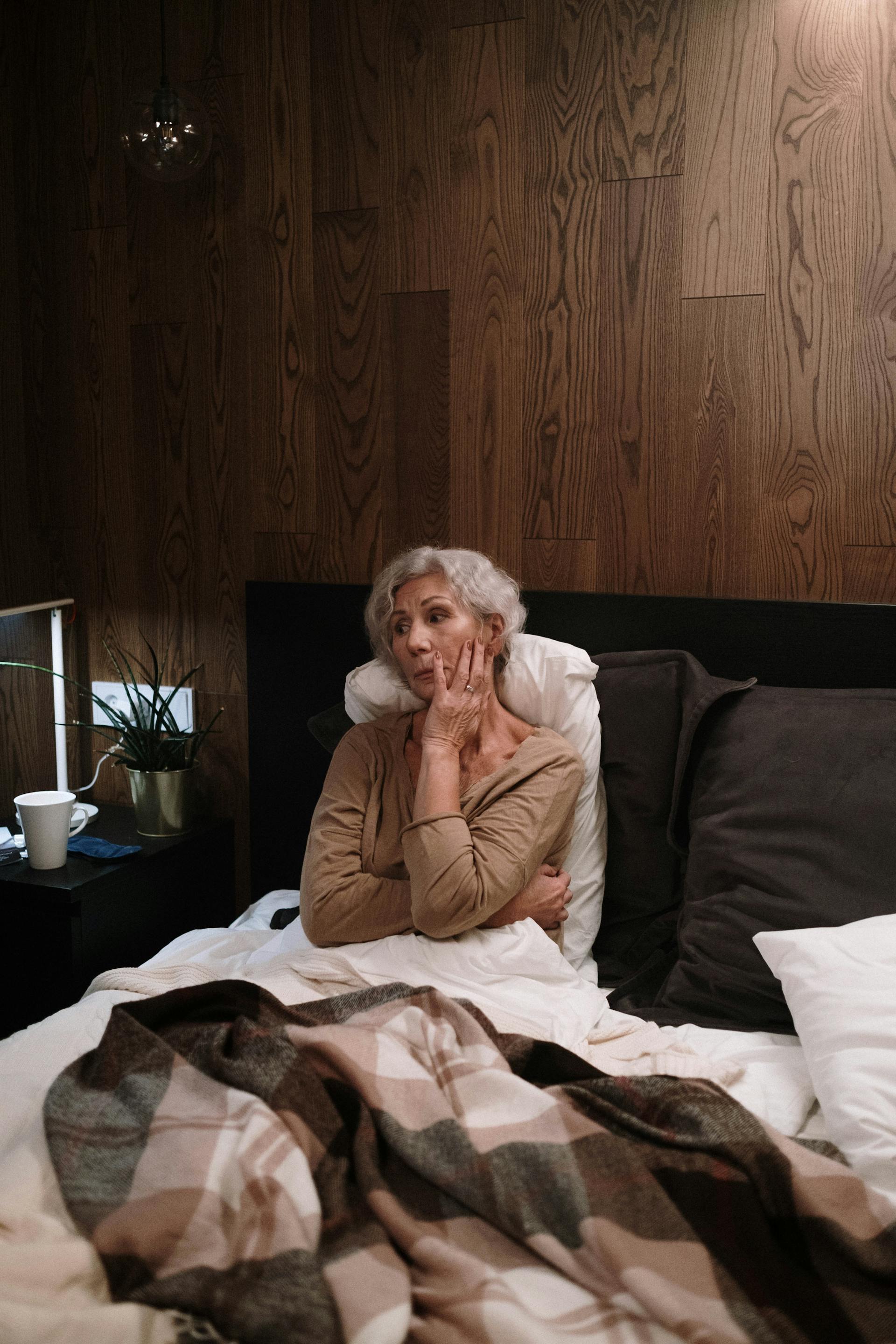 A sad elderly woman sitting in bed | Source: Pexels