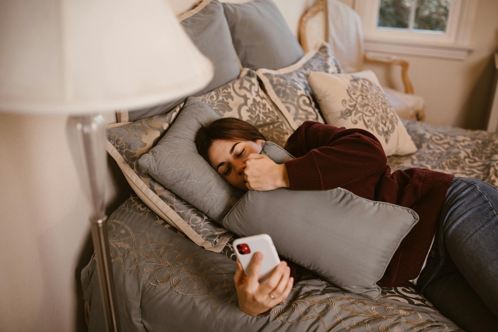 A woman checking her smartphone while lying in bed | Source: Pexels