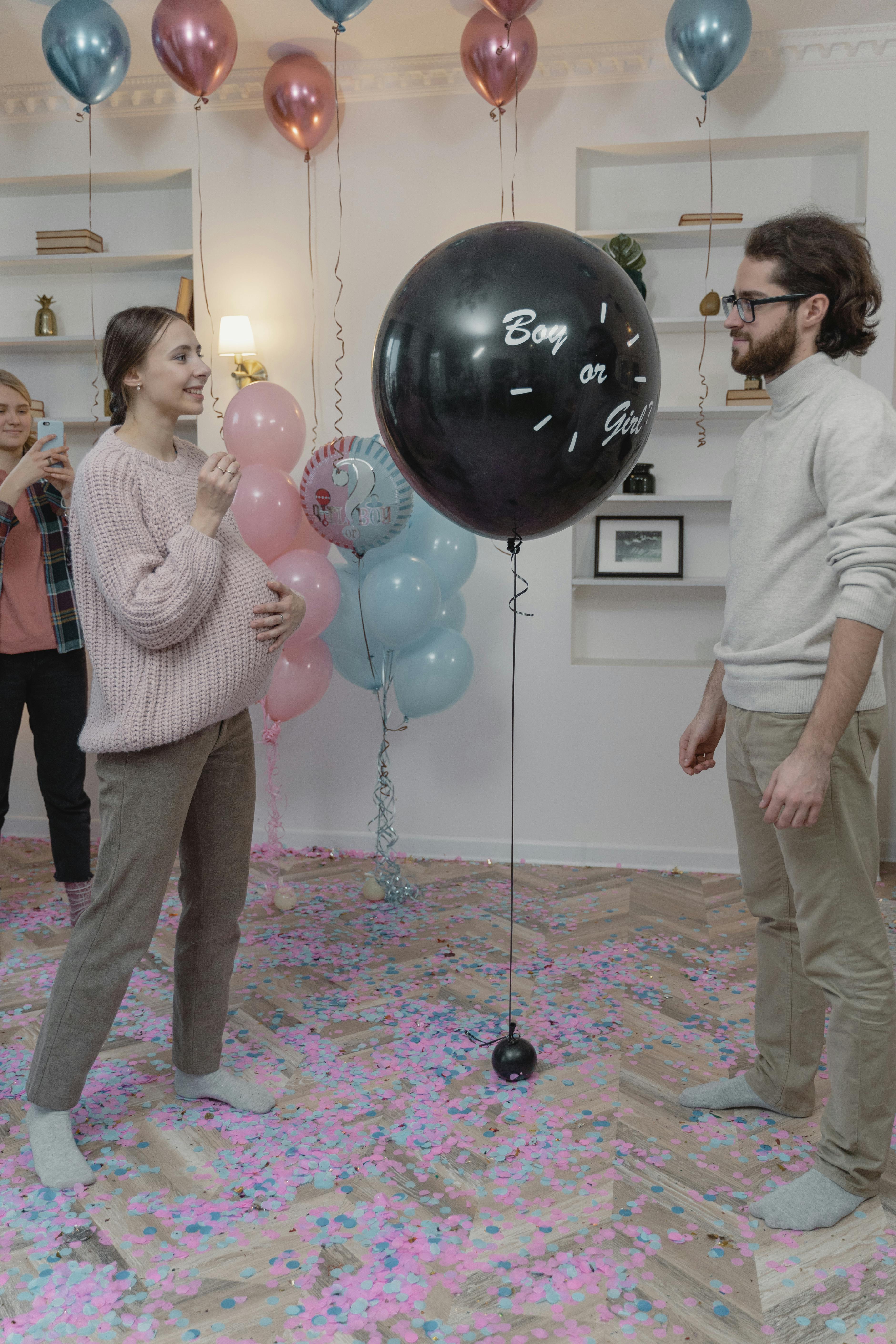 A couple about to pop a balloon at a gender reveal party | Source: Pexels