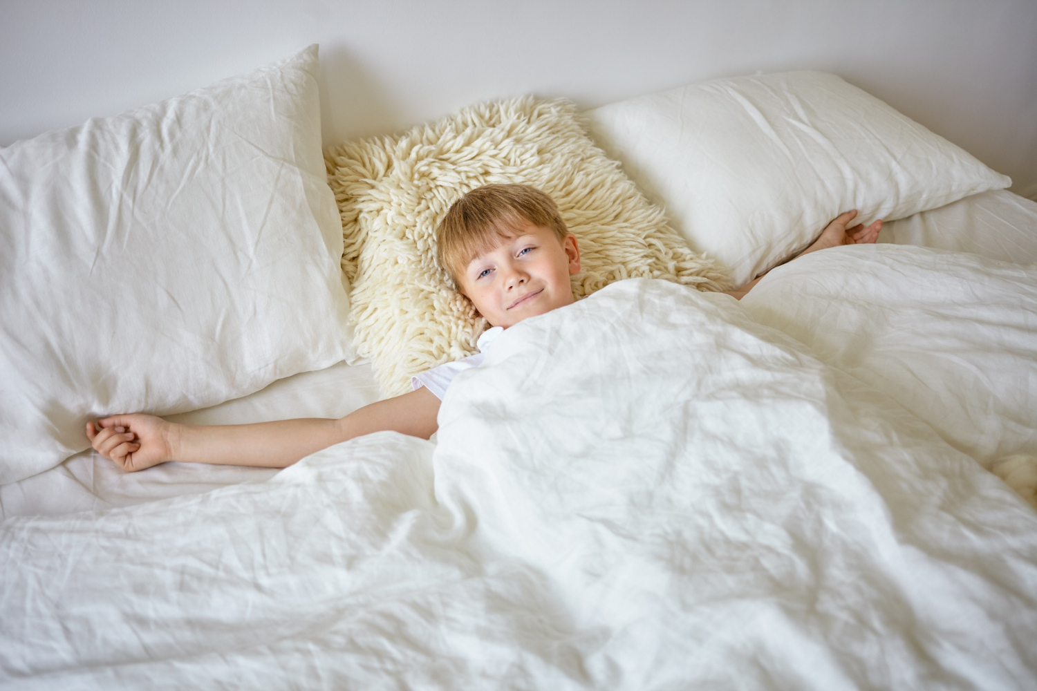A cheerful boy smiling from his bed | Source: Freepik