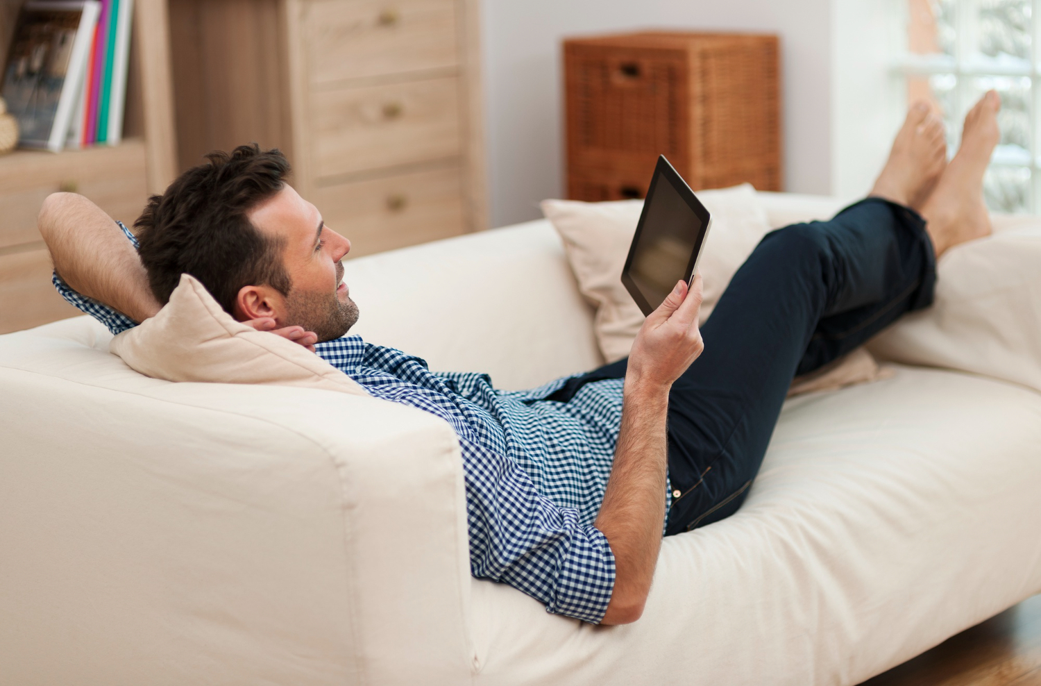 A man lying on the couch and using a digital tablet | Source: Freepik