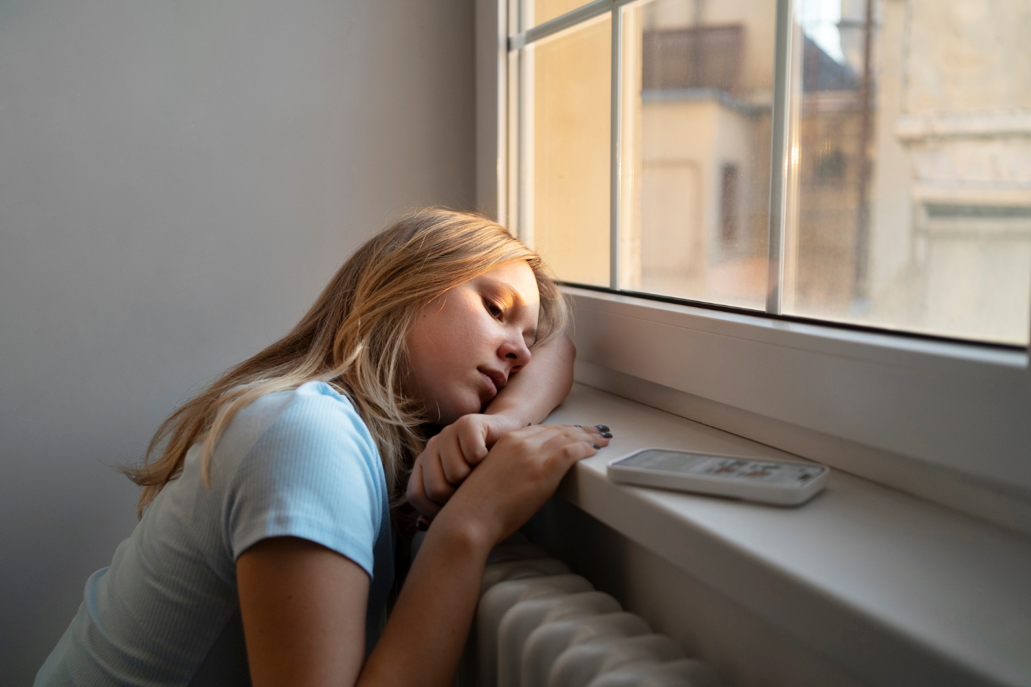 A sad teenage girl sitting by the window | Source: Freepik
