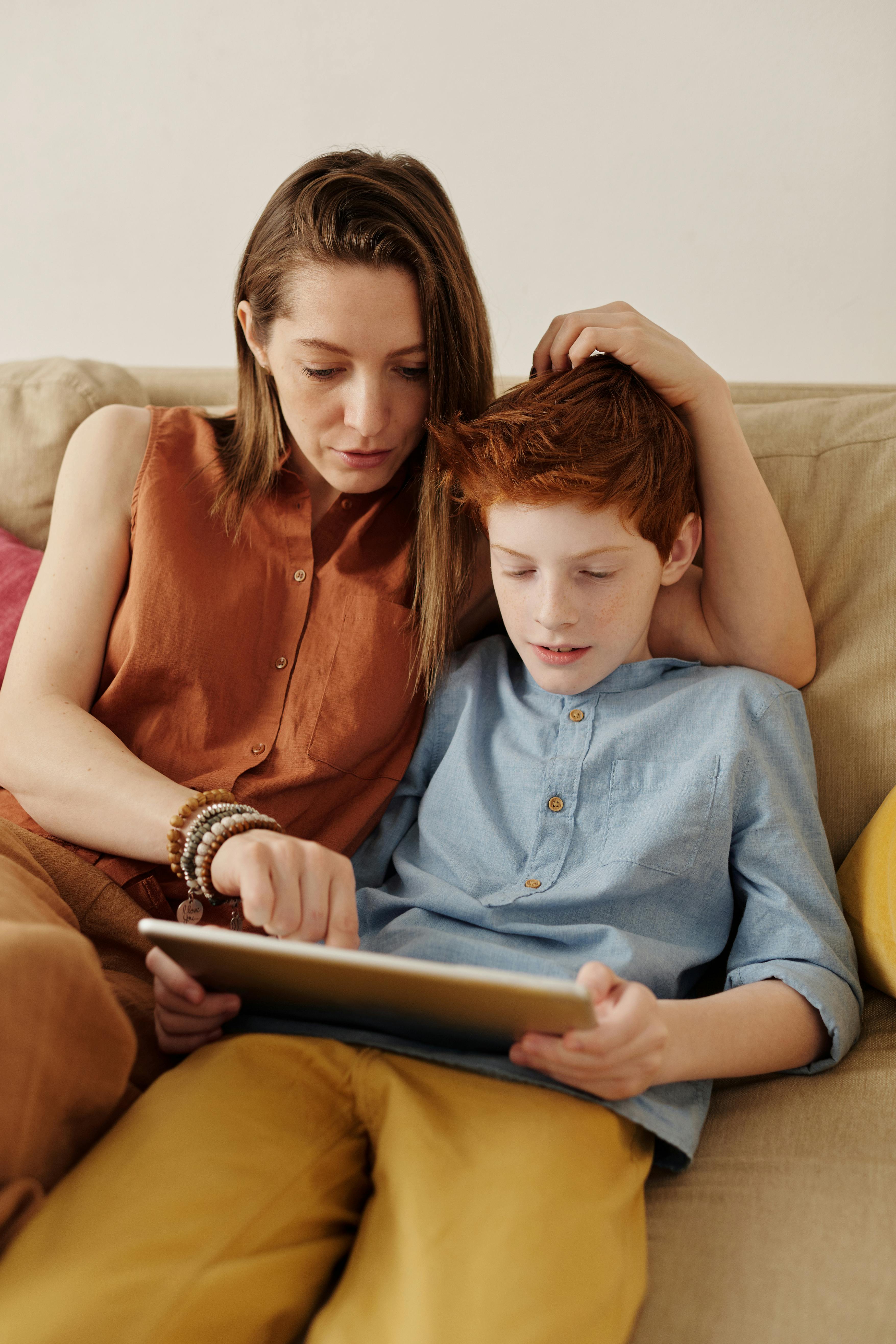 Mother and her son sitting on a couch looking at a tablet | Source:  Pexels