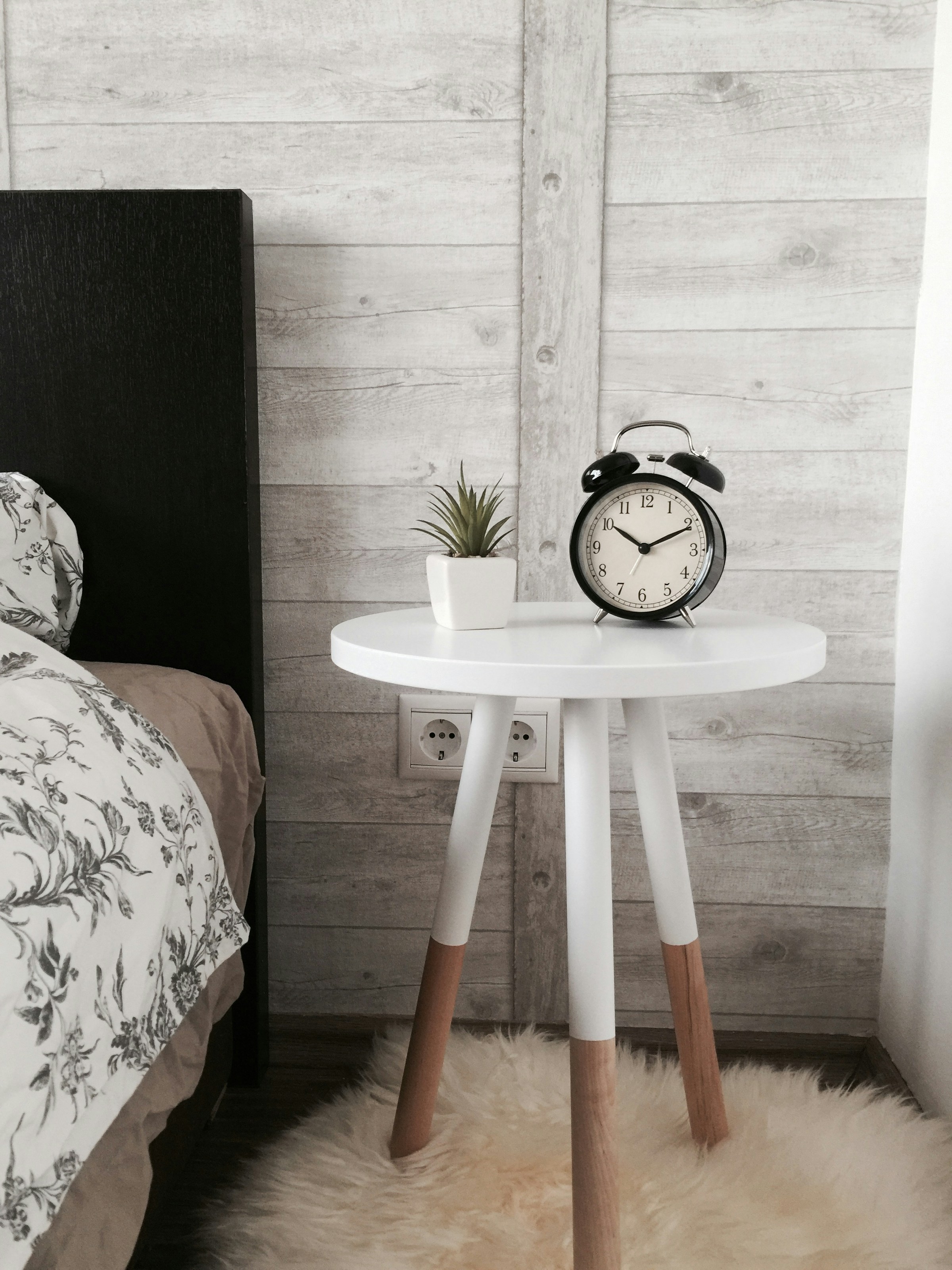 An alarm clock lying on a wooden table in a room | Source: Unsplash