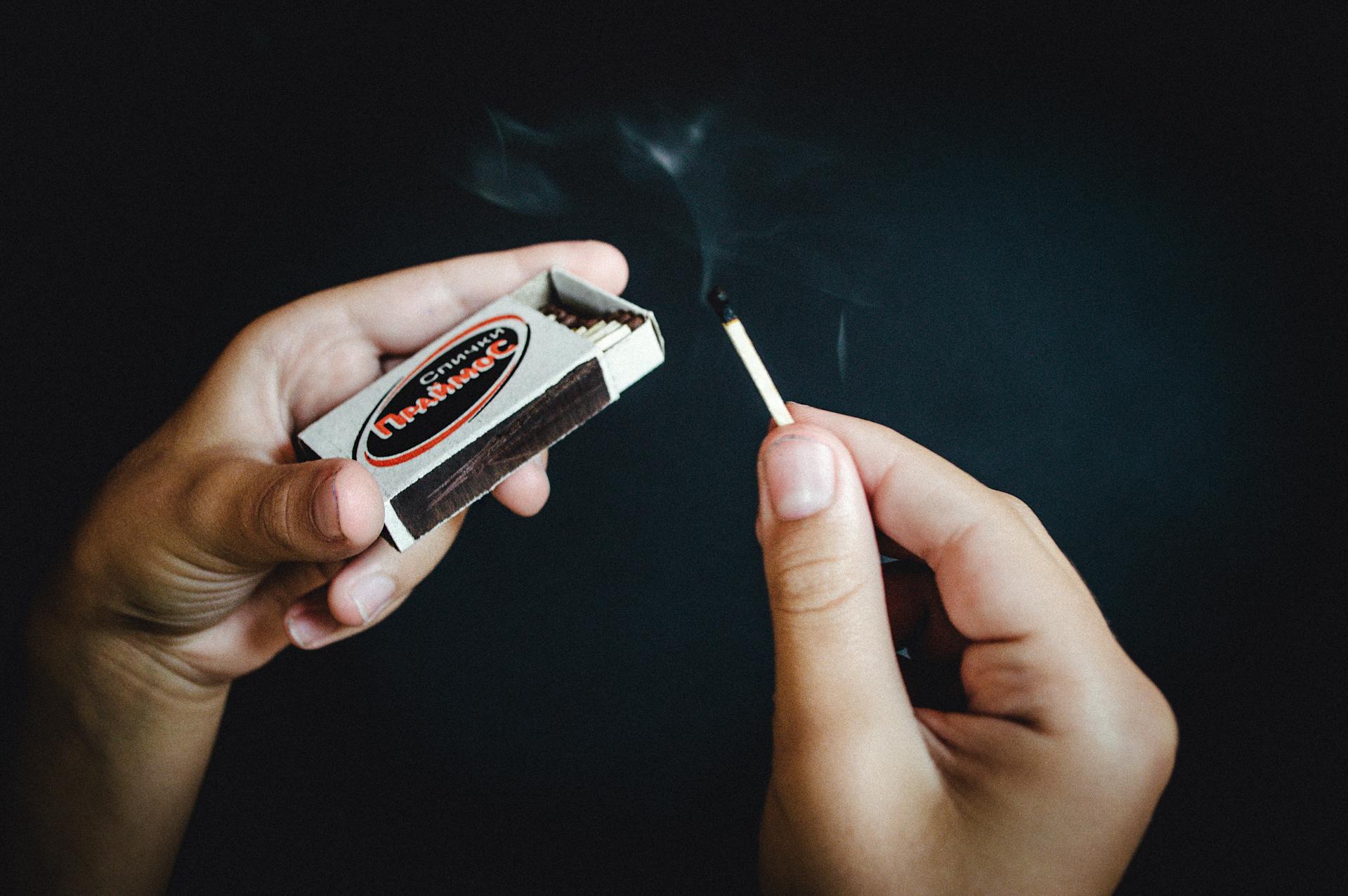 A person holding a matchstick and a matchbox | Source: Pexels