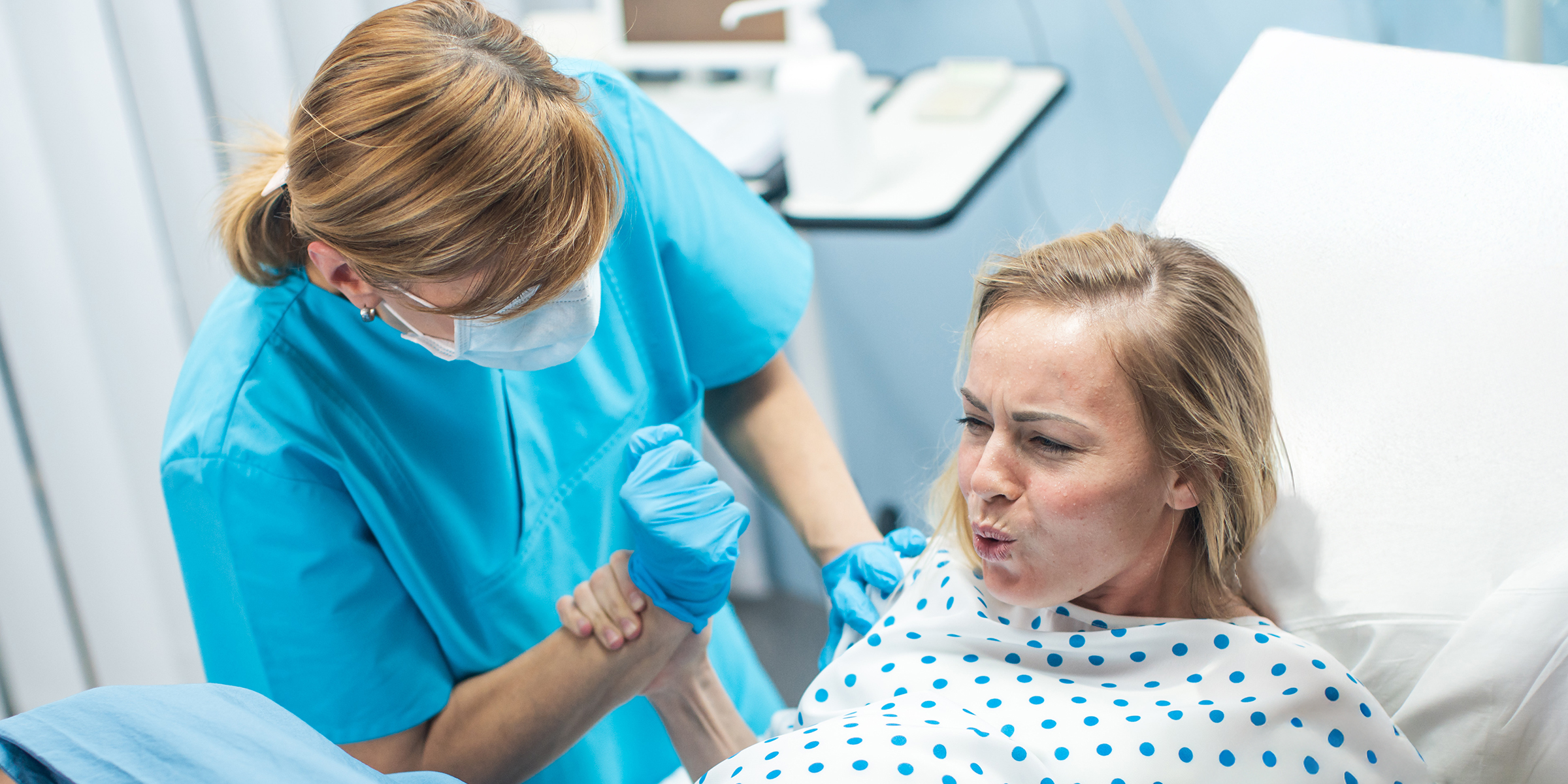 A woman holding a nurse's hand in a hospital room | Source: Shutterstock