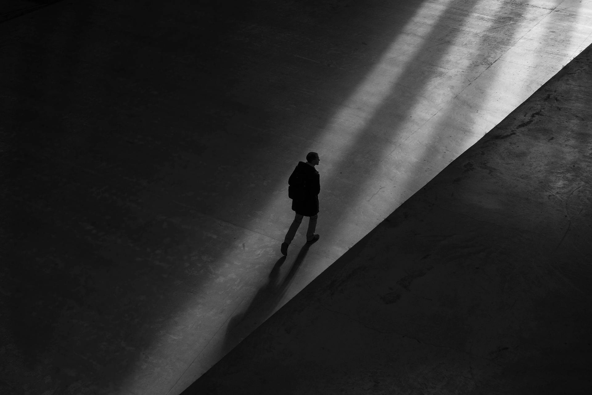 Grayscale silhouette of a man walking alone | Source: Pexels