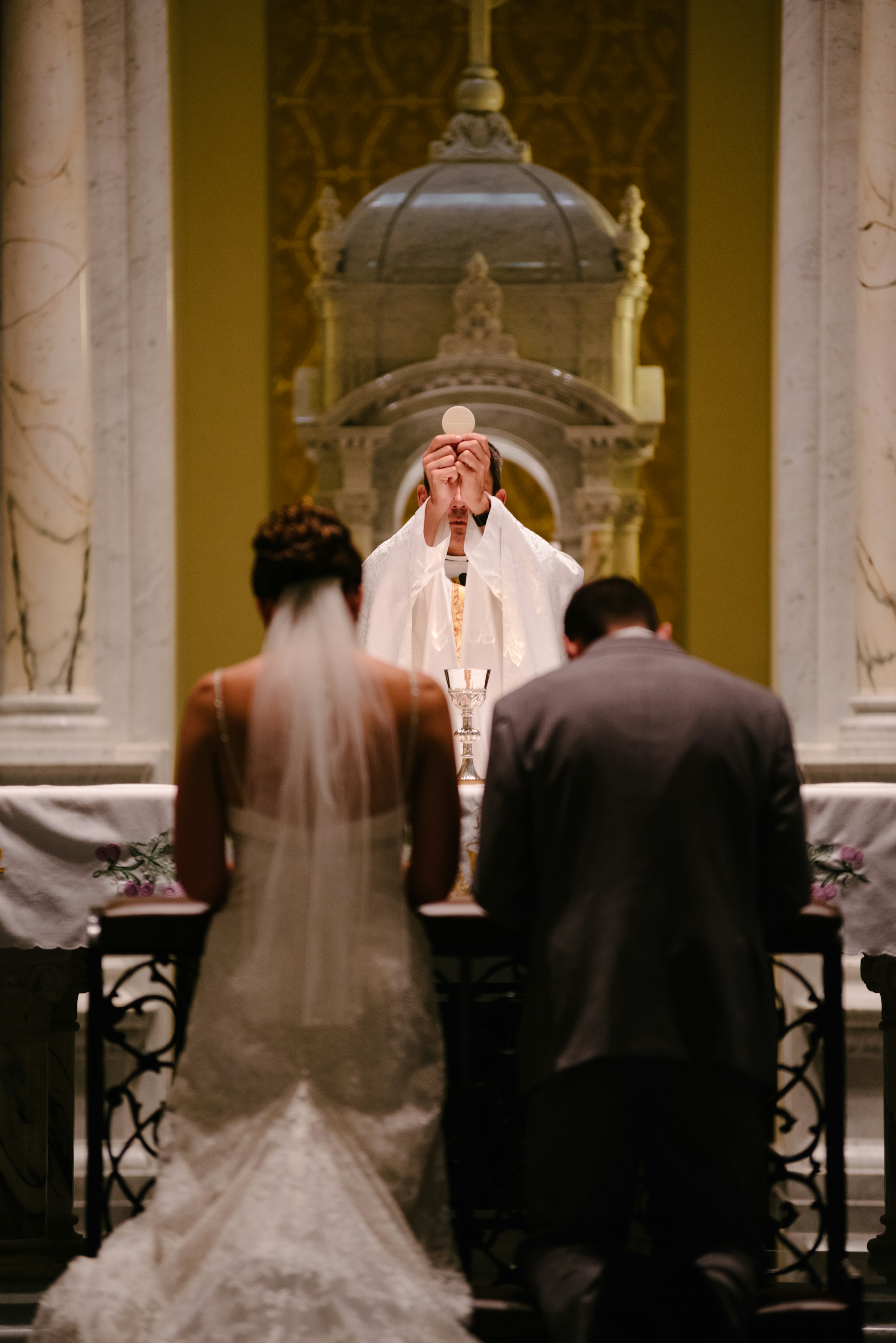 A couple kneeling before a priest | Source: Unsplash