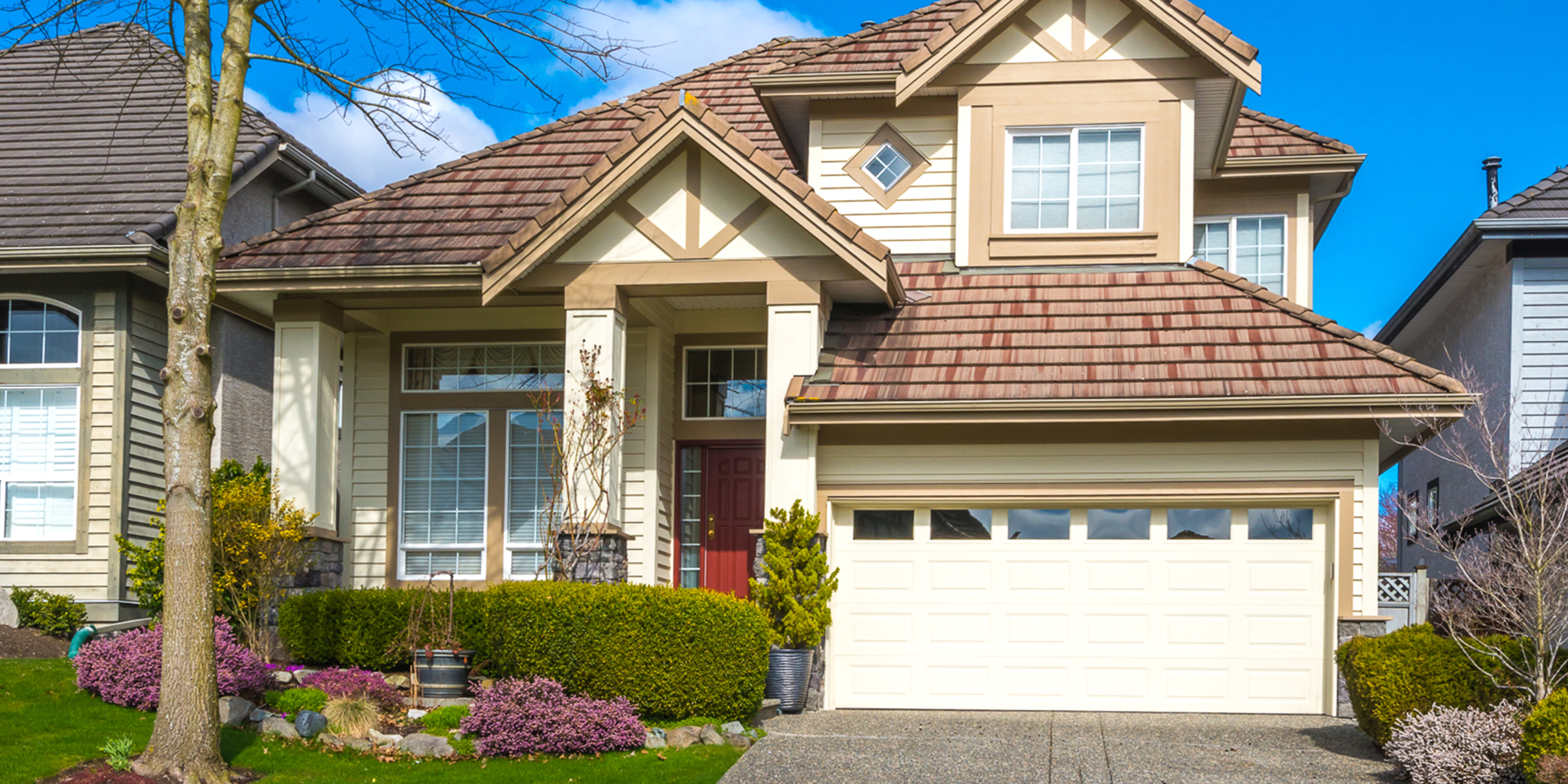 A suburban home with a red front door, manicured landscaping, and a bright, welcoming exterior | Source: Shutterstock