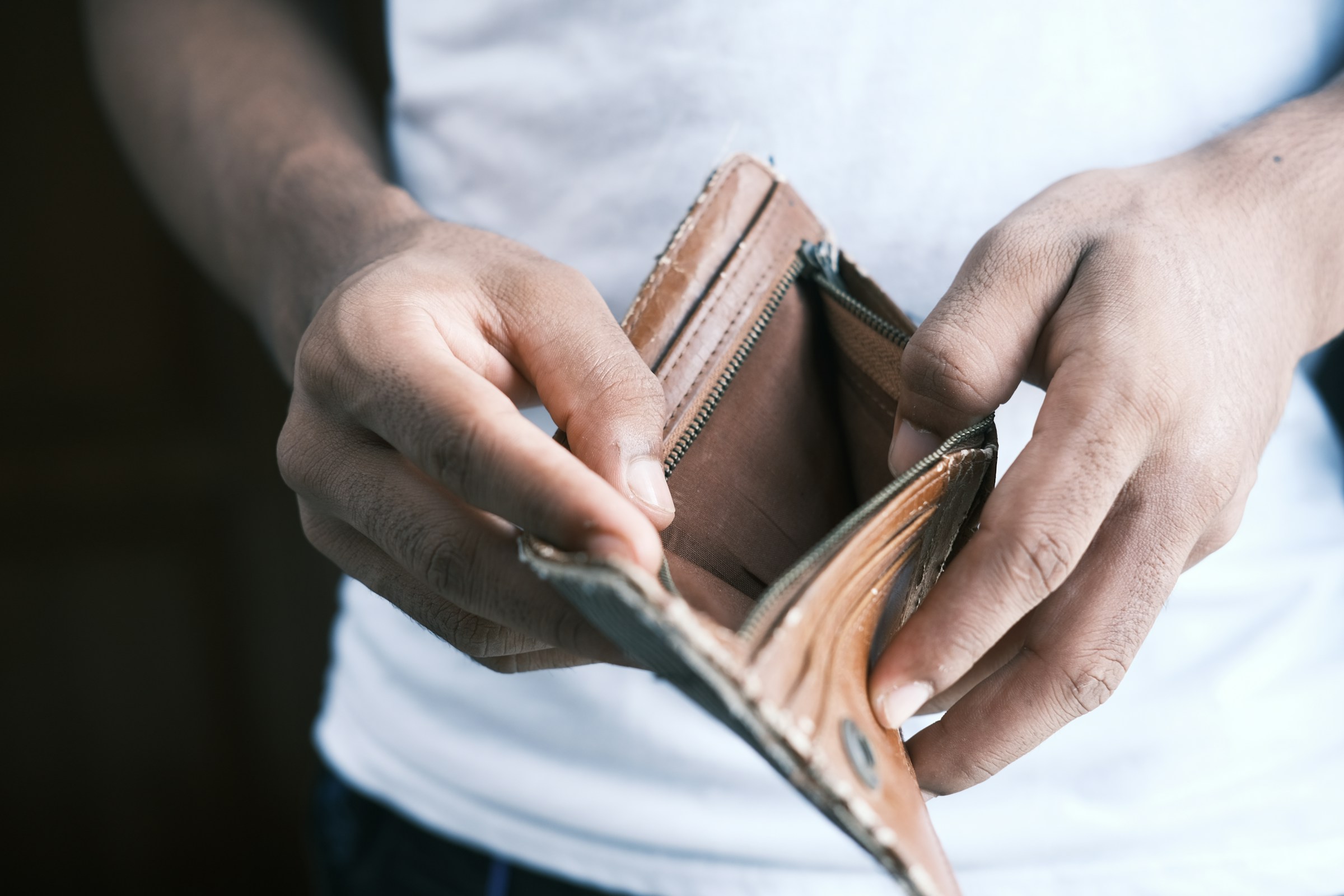 Un hombre abriendo una billetera vacía | Fuente: Unsplash