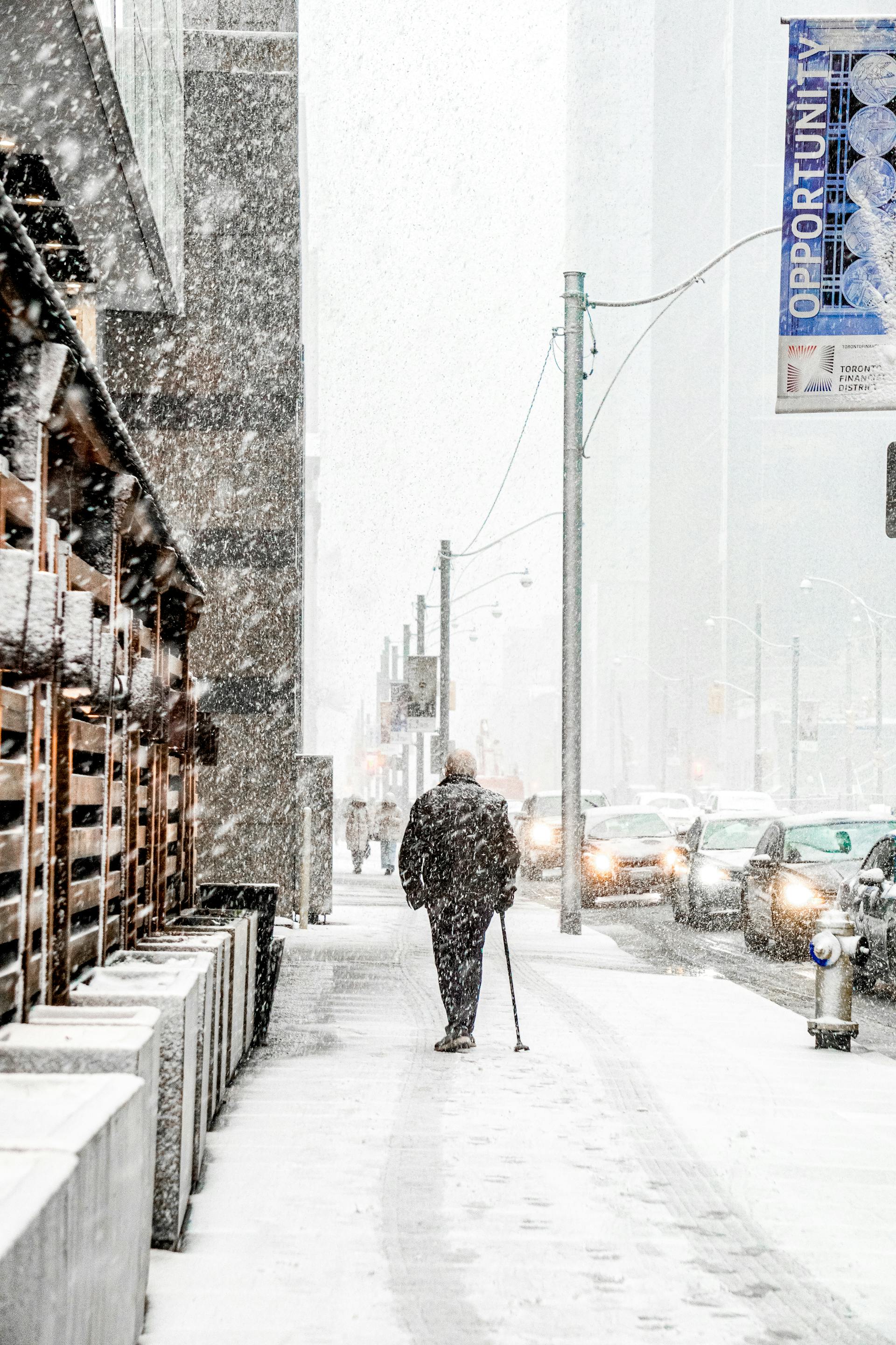 A back-view of an old man walking on a sidewalk in snowfall | Source: Pexels