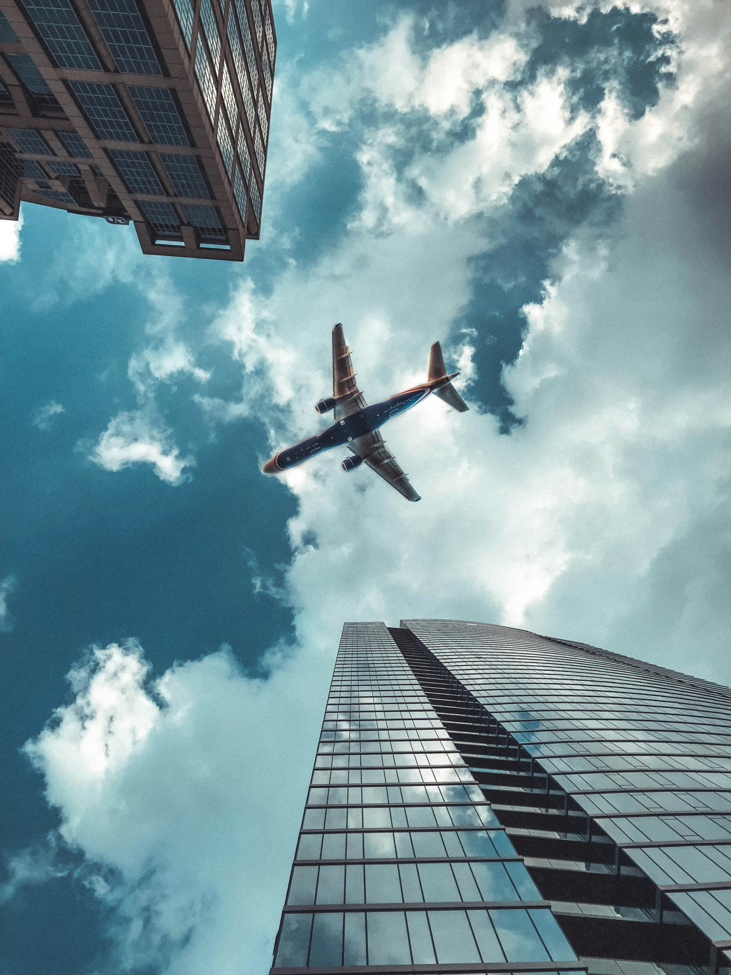 Shot of an airplane passing above high-rise buildings | Source: Unsplash