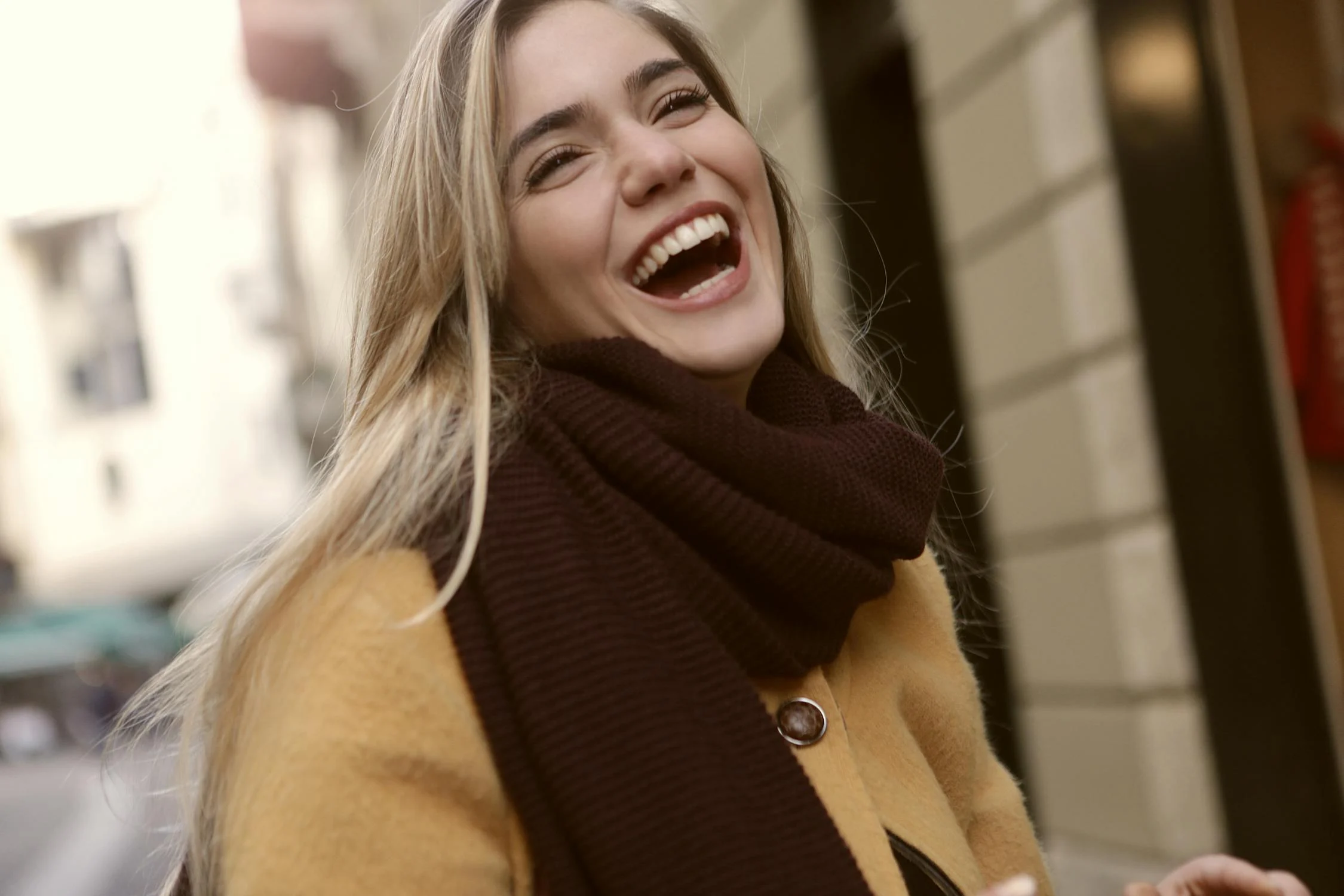 A laughing blonde woman outside ⏐ Source: Pexels