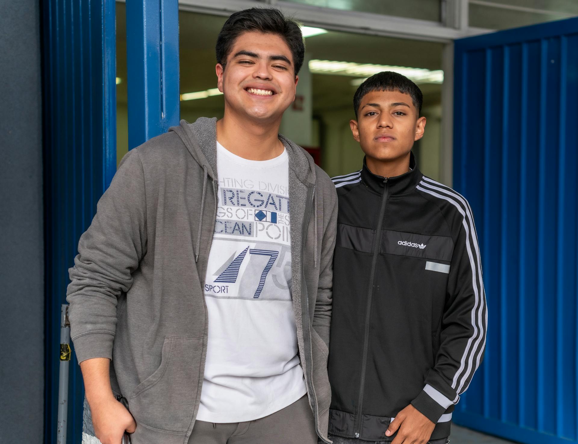Two young men standing in front of a blue door | Source: Pexels