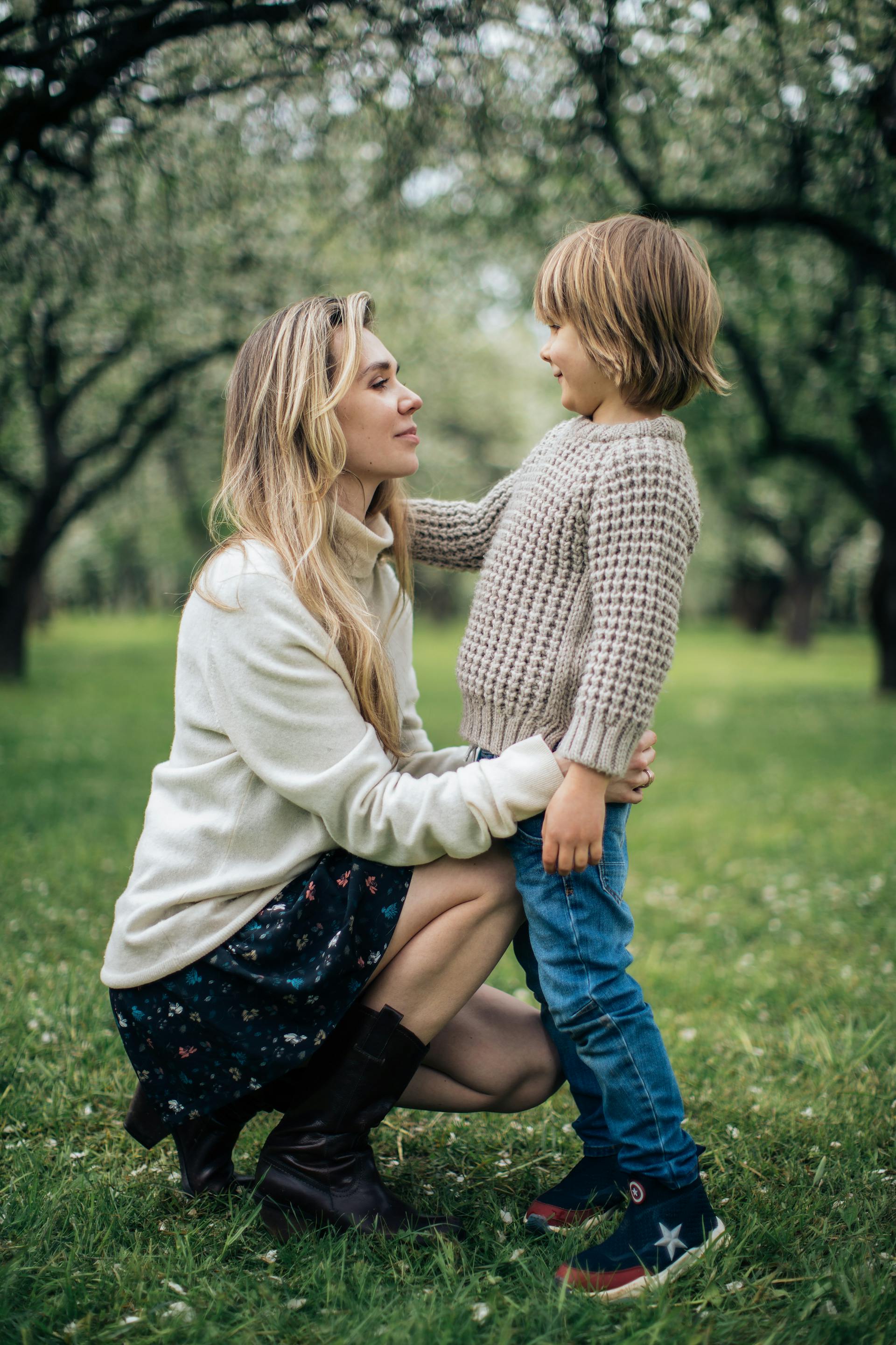 A woman standing on a grass field with her son | Source: Pexels