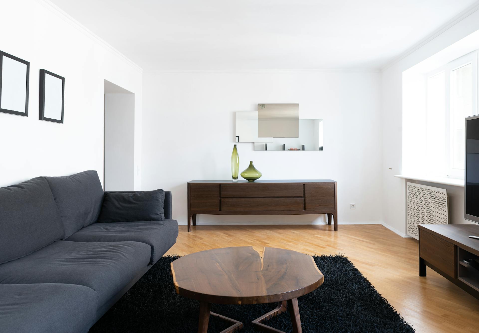A clean living room with a black couch, a wooden coffee table, and a brown cabinet | Source: Pexels