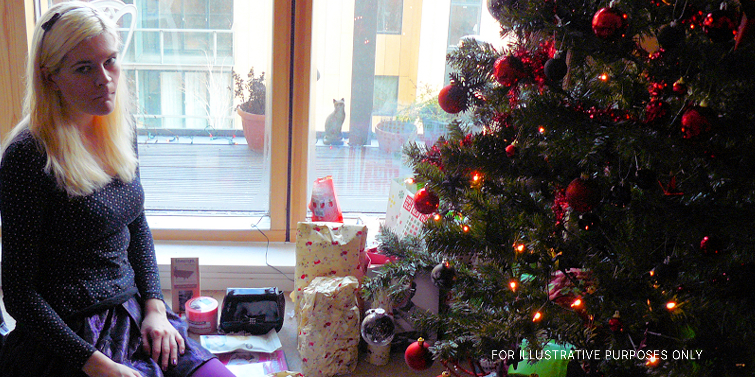 A sad woman sitting beside a Christmas tree | Source: flickr.com/Mike_fleming/CC BY 2.0