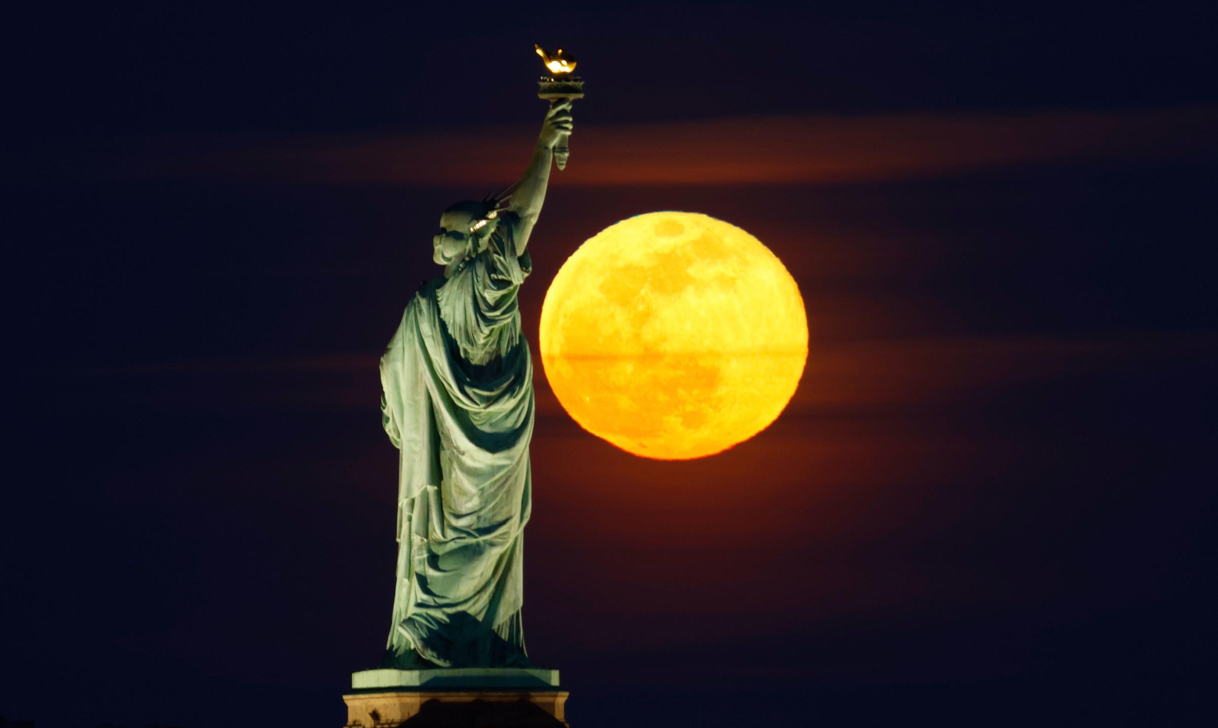 The full Snow Moon rises behind the Statue of Liberty and Brooklyn in New York City on February 24, 2024, as seen from Jersey City, New Jersey | Source: Getty Images