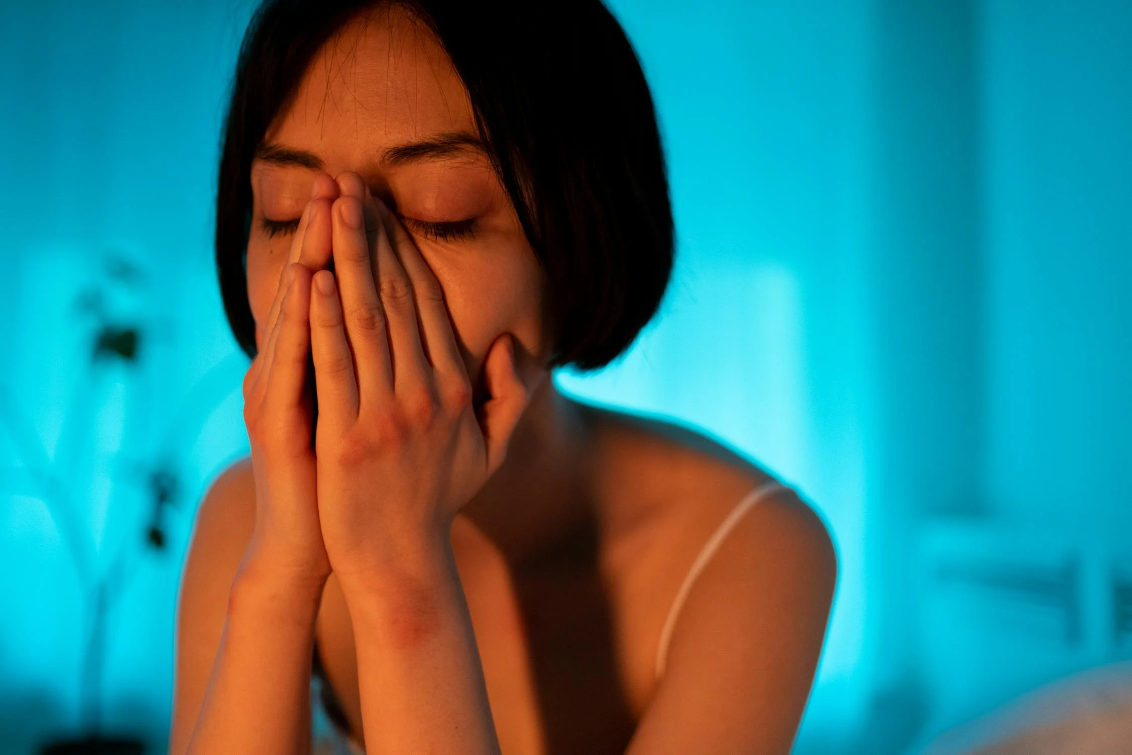 A sad woman in a room with blue light | Source: Pexels