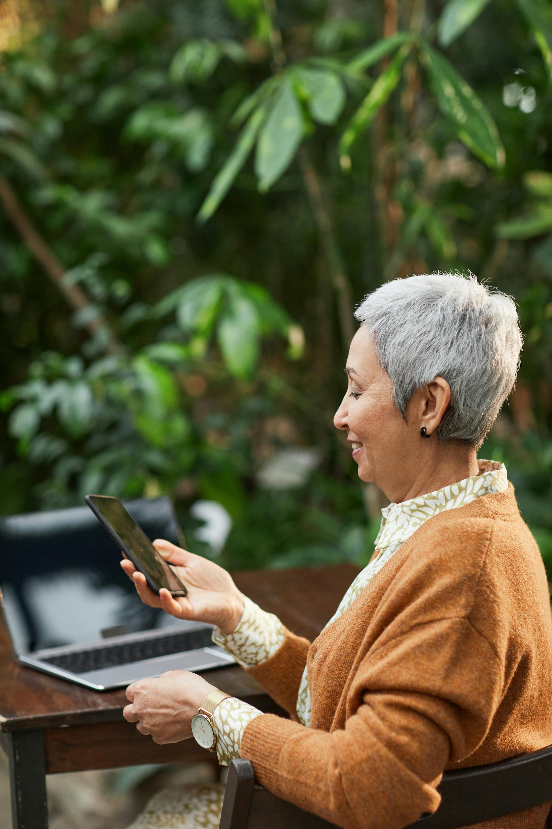 A senior woman smiles while looking at her phone | Source: Pexels