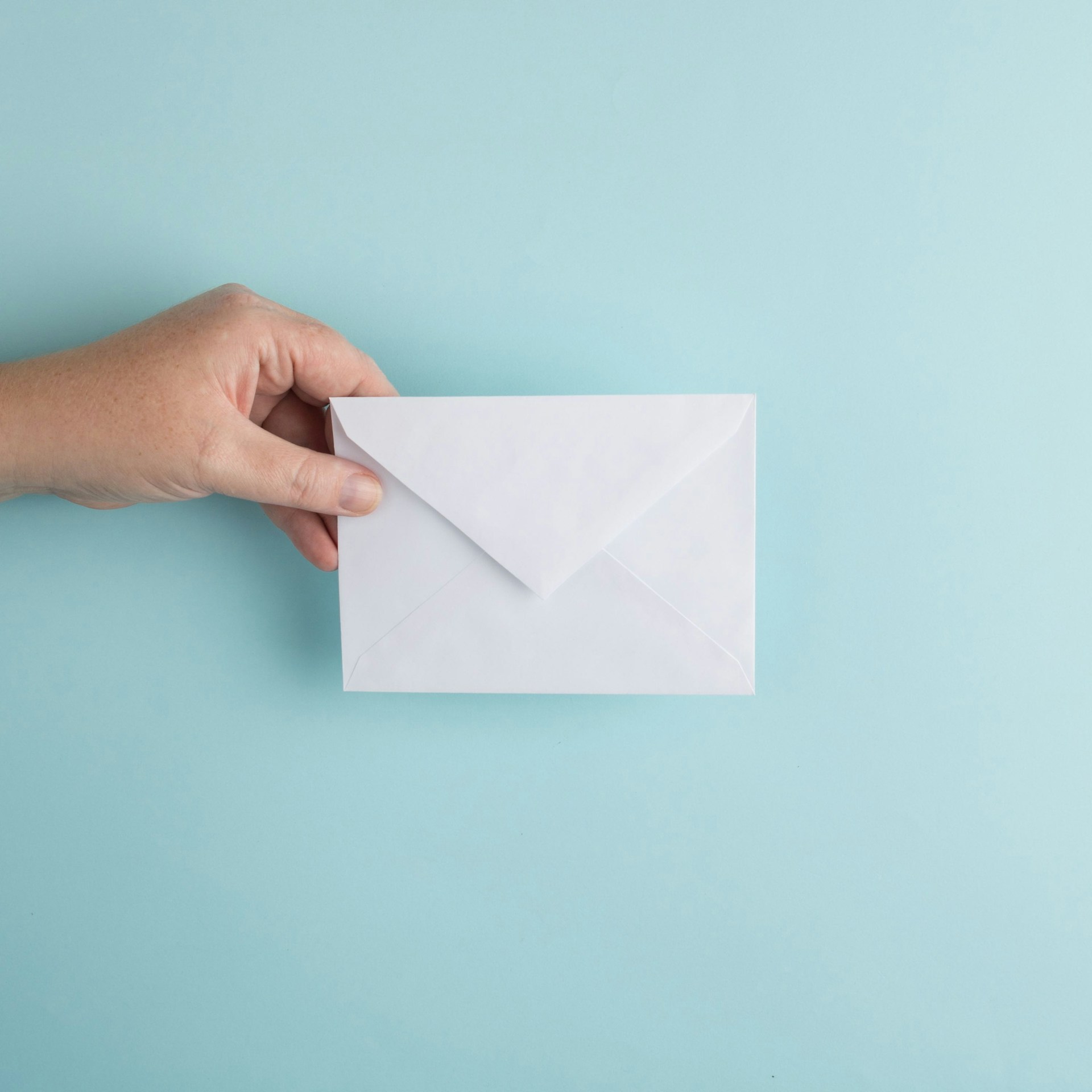 A man's hand holding an envelope | Source: Unsplash