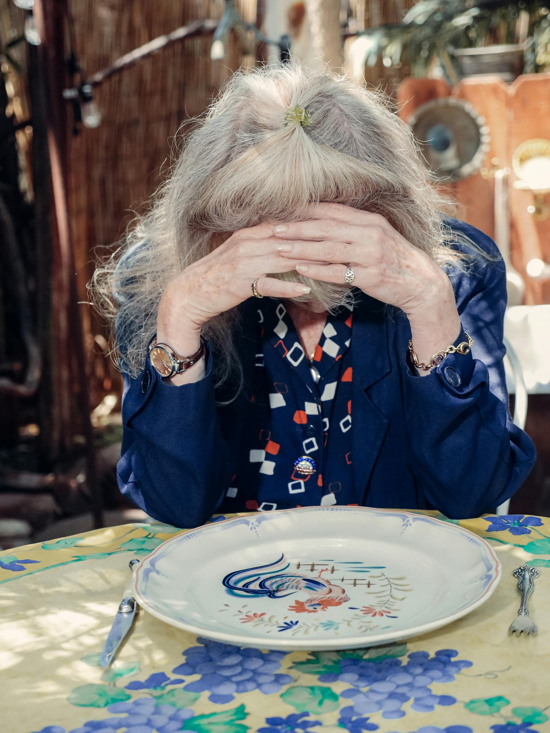 A distressed elderly woman covering her face | Source: Pexels