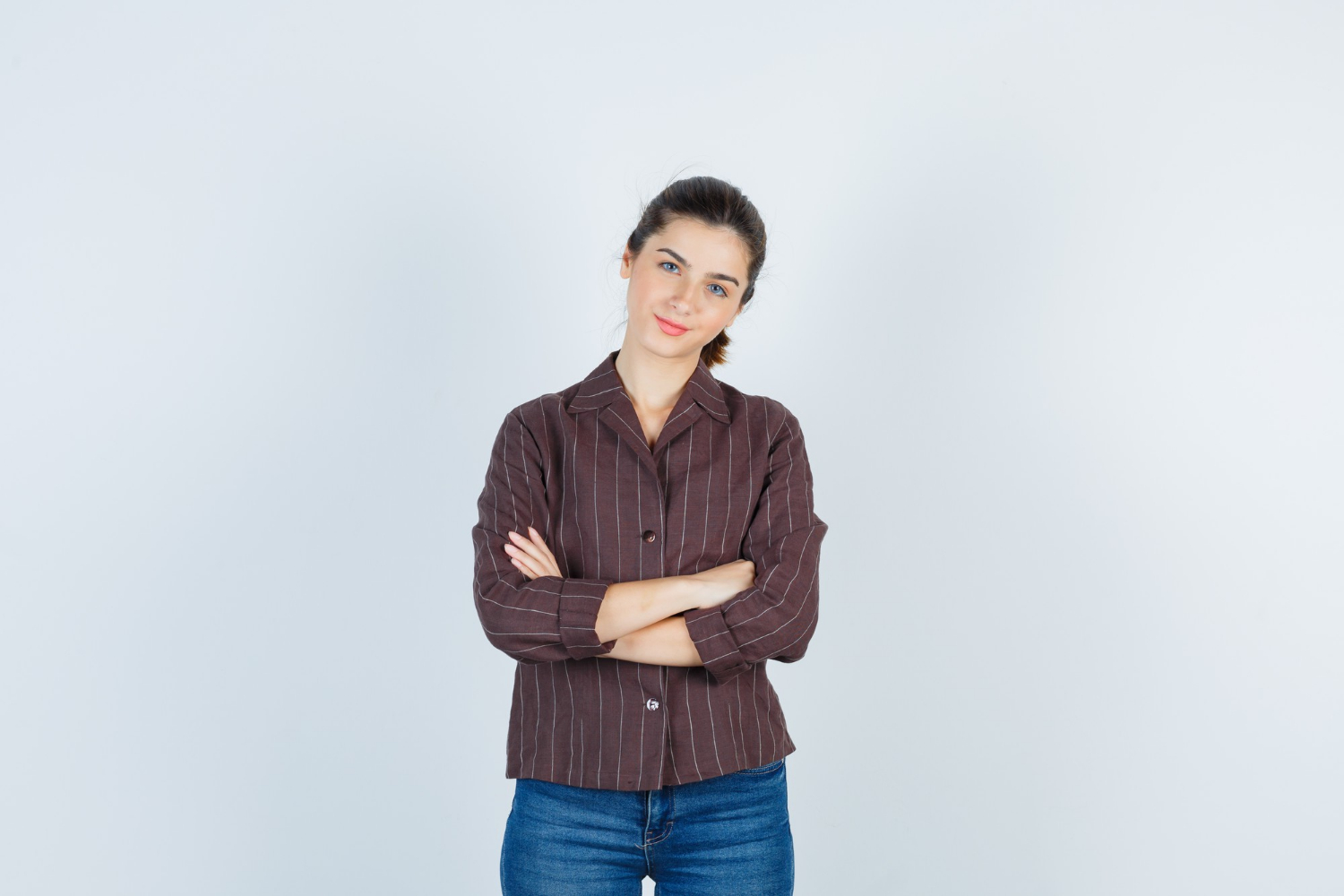 A smiling young woman with her arms crossed | Source: Freepik