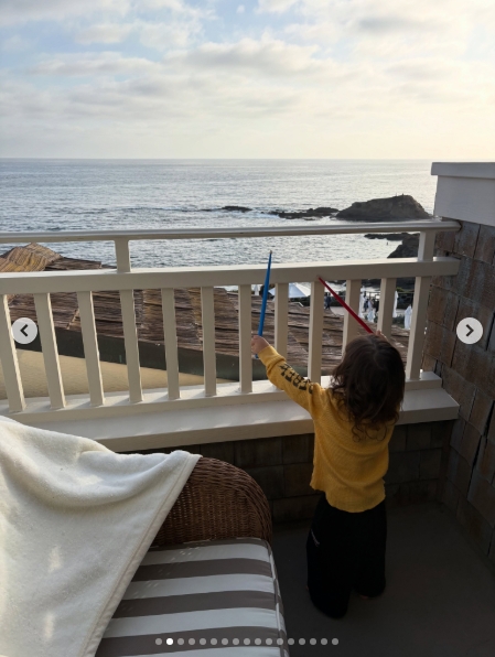 Rocky Thirteen stood on a balcony overlooking the ocean while holding red and blue drumsticks in a photo shared by Kourtney Kardashian Barker in a post dated May 27, 2026. | Source: Instagram/kourtneykardash