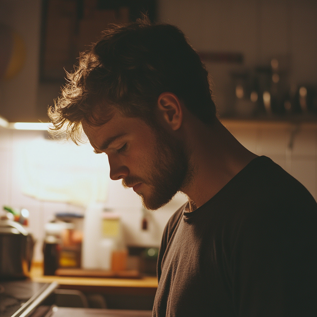 A serious man looking down in his kitchen | Source: Midjourney