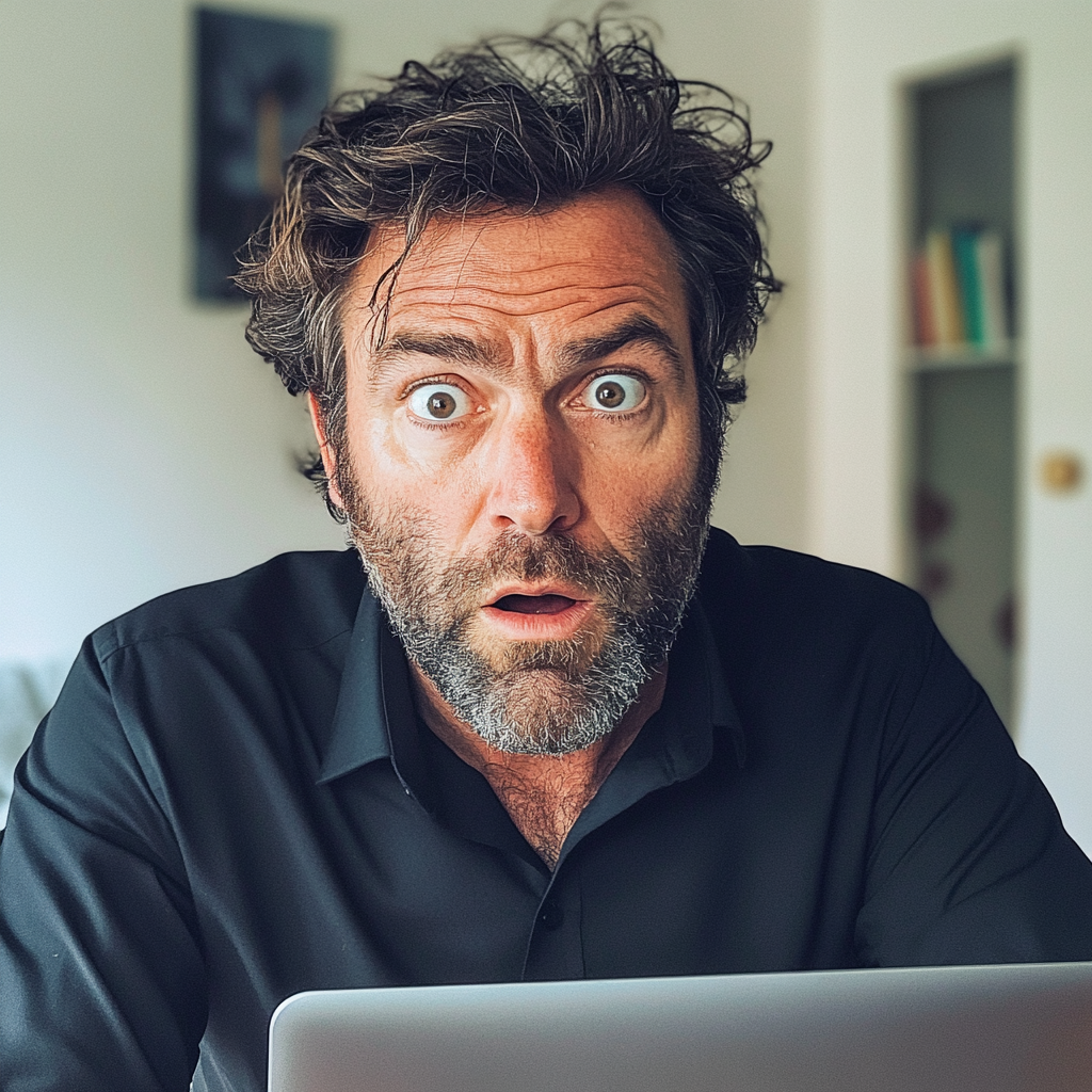 A wide-eyed man sitting with his computer | Source: Midjourney
