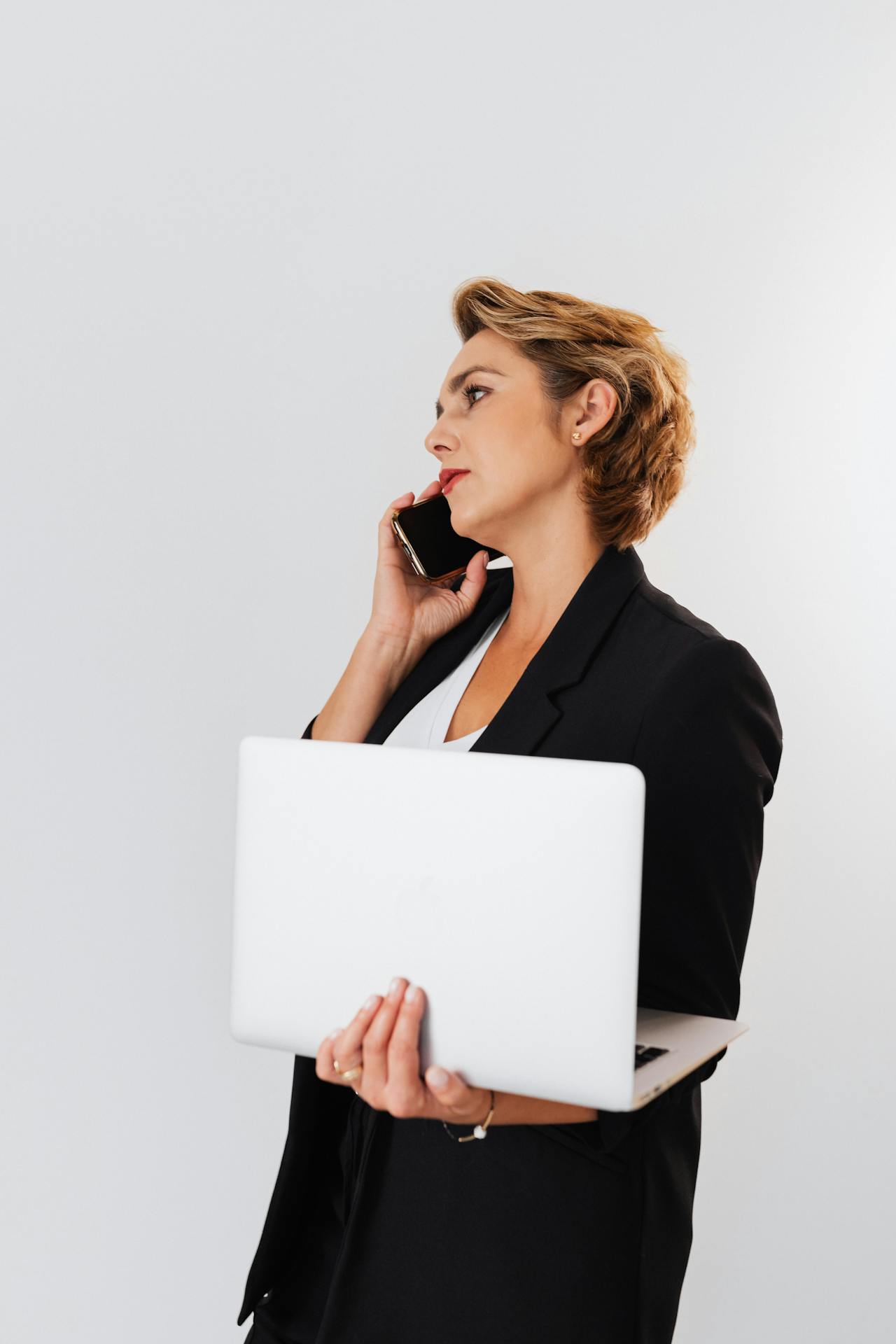 A woman engaged on a phonecall while holding a laptop | Source: Pexels